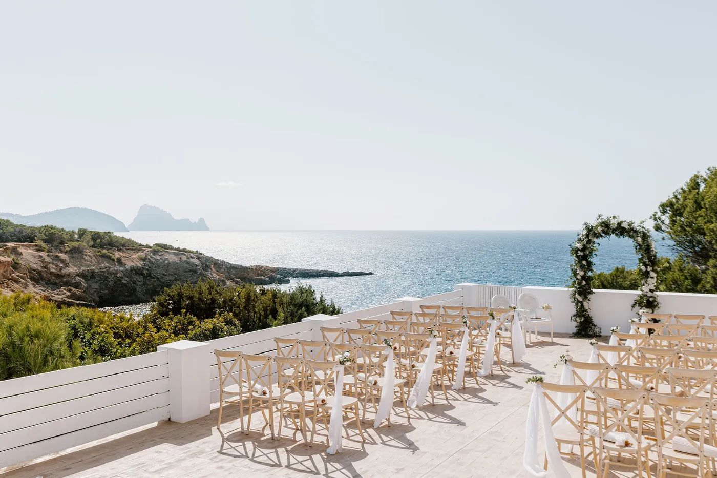 Golden chairs and a floral arch on a terrace overlooking the Ibiza coast for a destination wedding in Spain
