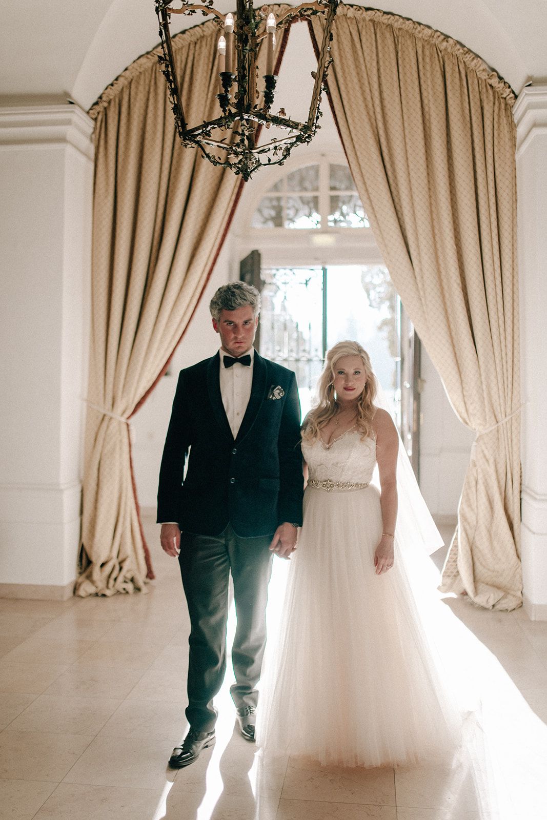 Bride and groom walking through a curtained hall on their elopement day in Austria