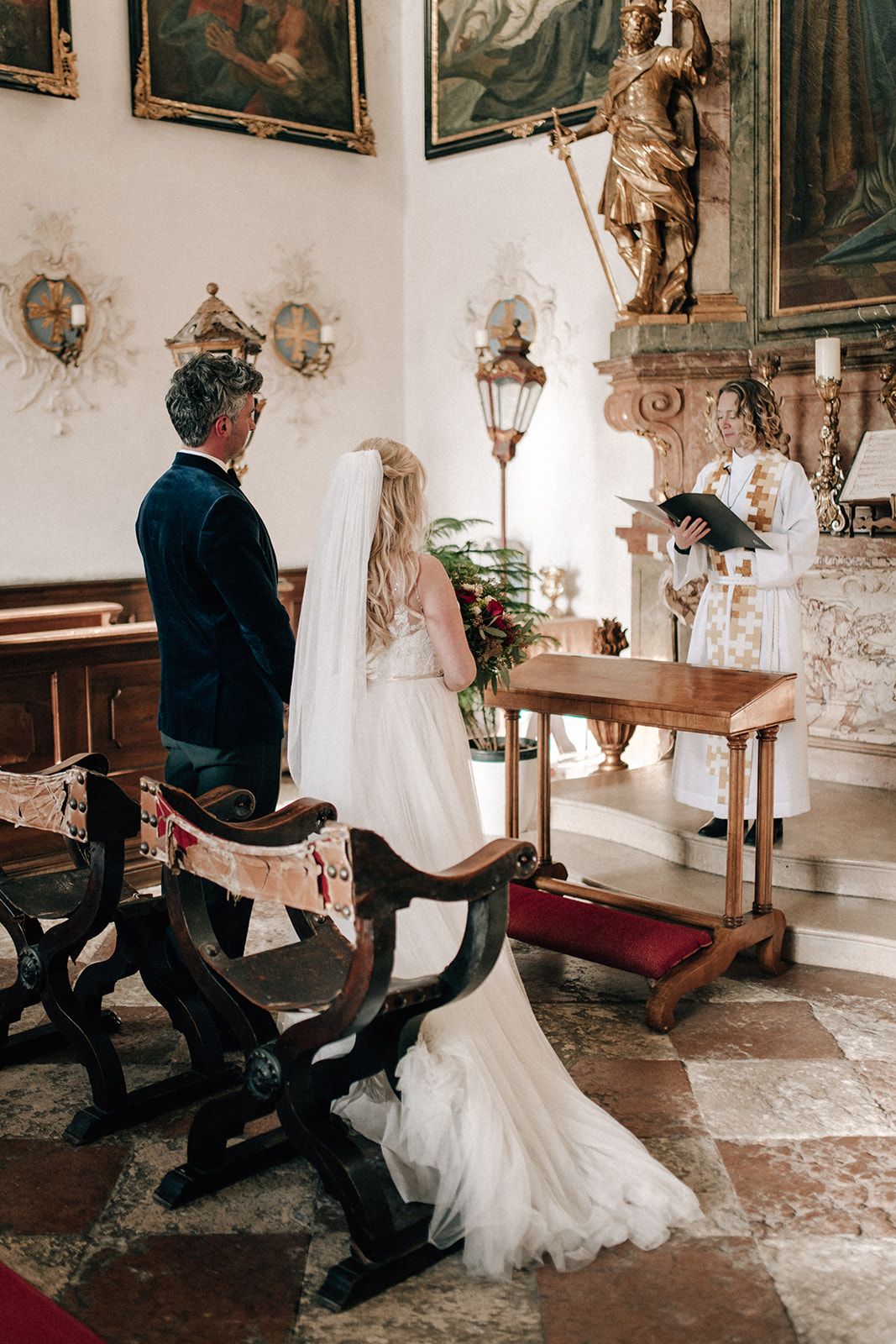 Couple exchanging vows before the priest at the altar of a historic Austrian chapel