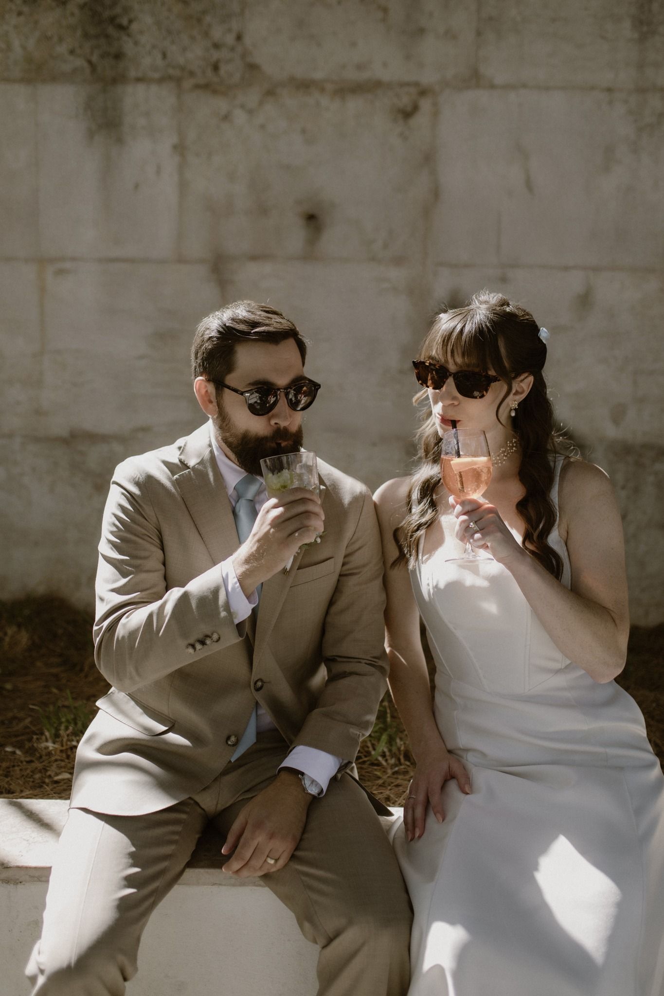 Bride and groom drink cocktails under the autumn sun during the photoshoot of their small wedding in Portugal