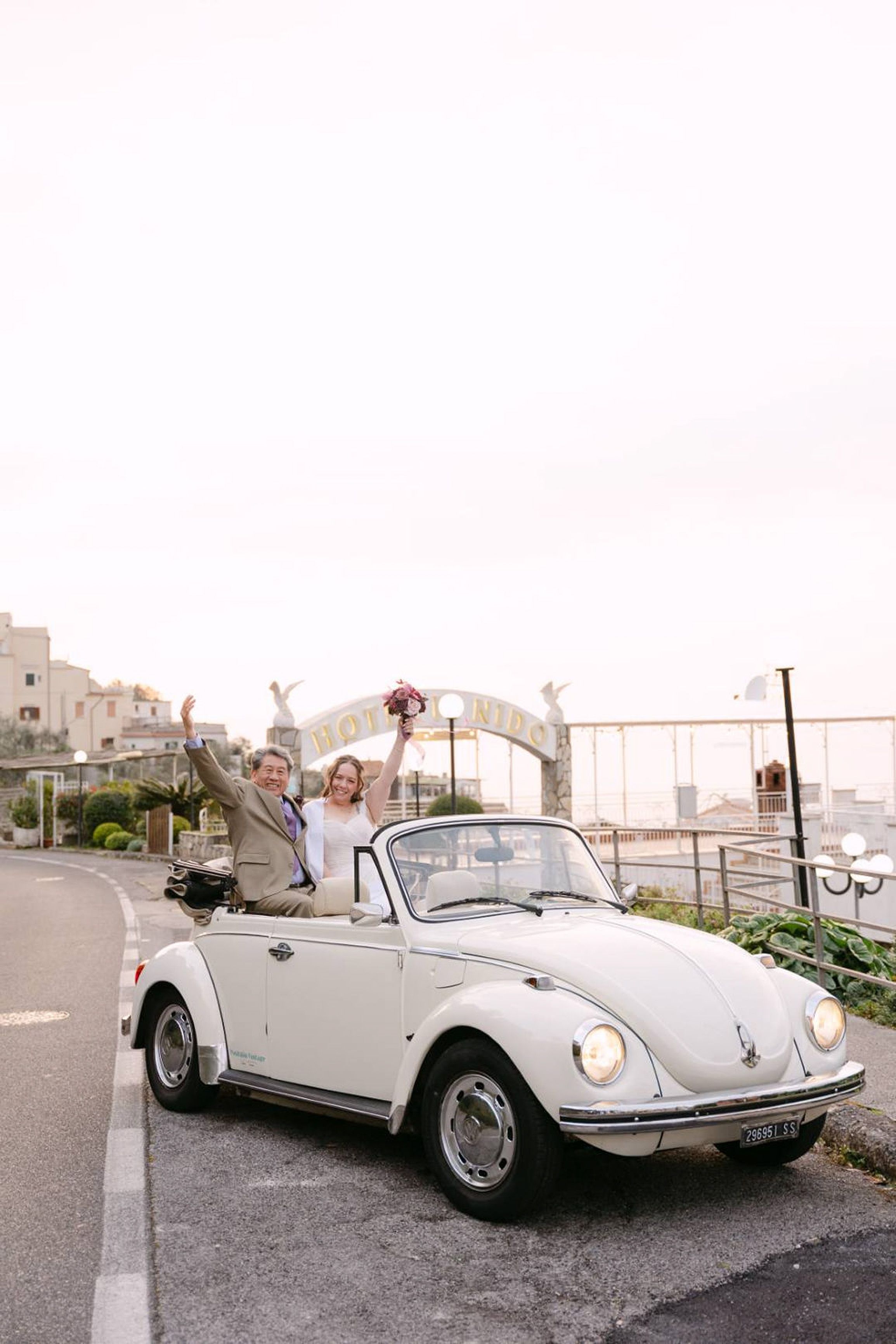 Newlyweds celebrating in a vintage convertible after a small wedding in Italy