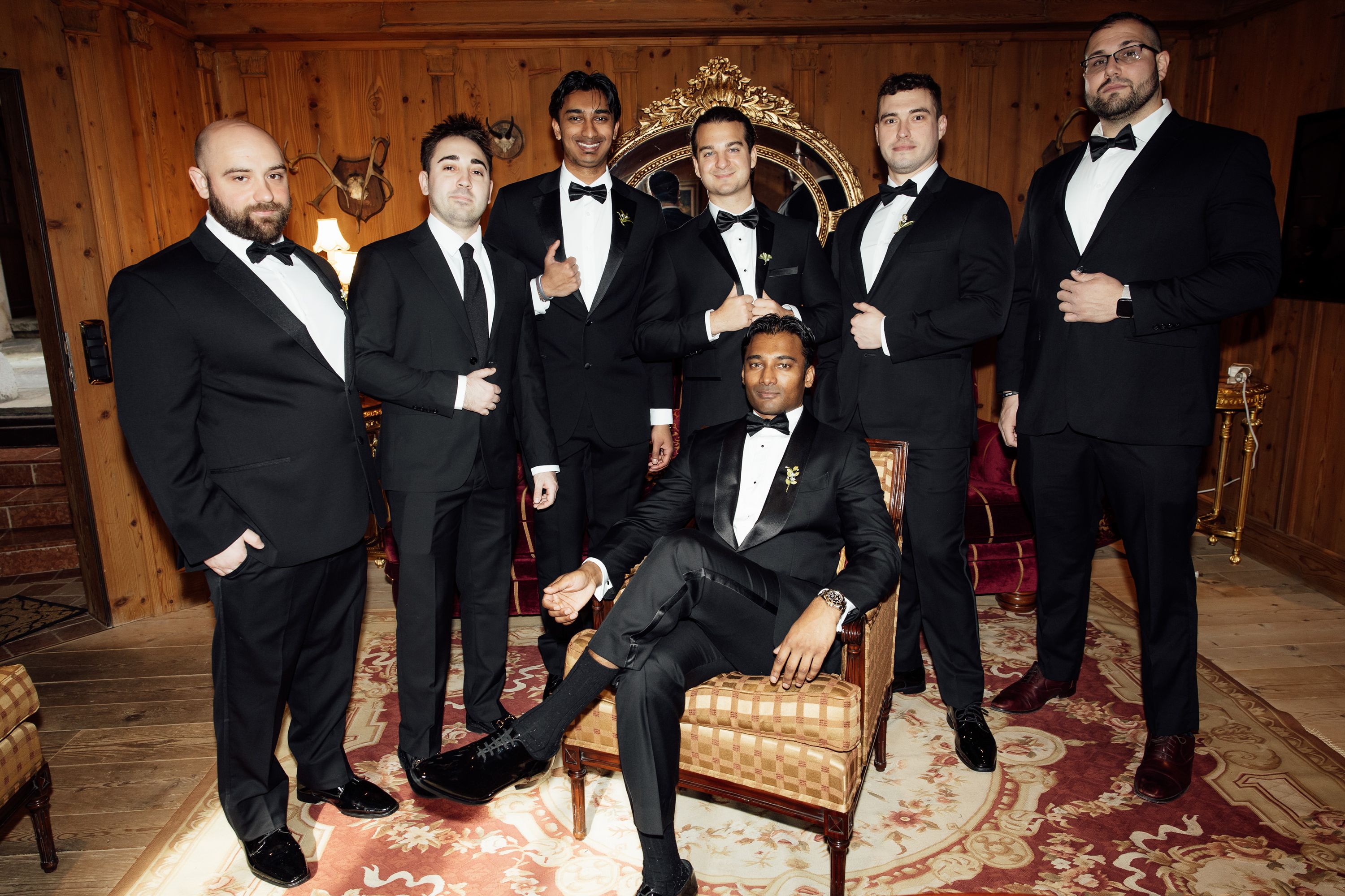Groomsmen in black tuxedos pose together before an intimate wedding in Austria at a rustic alpine venue