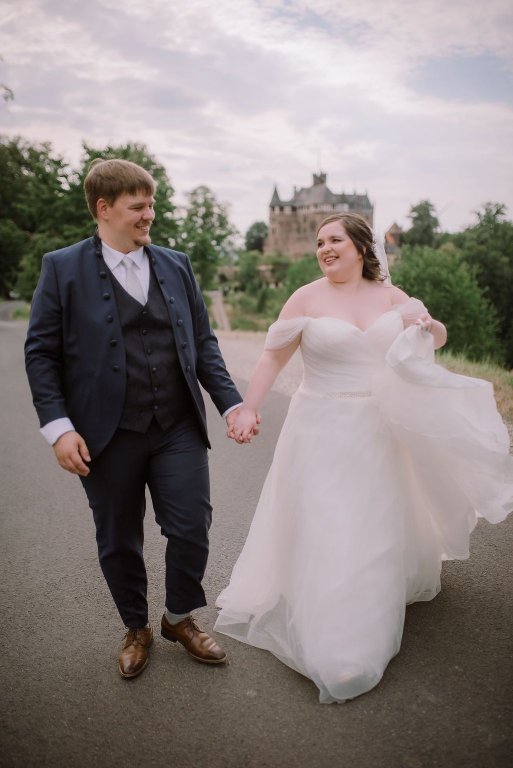 A bride and groom walking past a castle during their small wedding in Germany