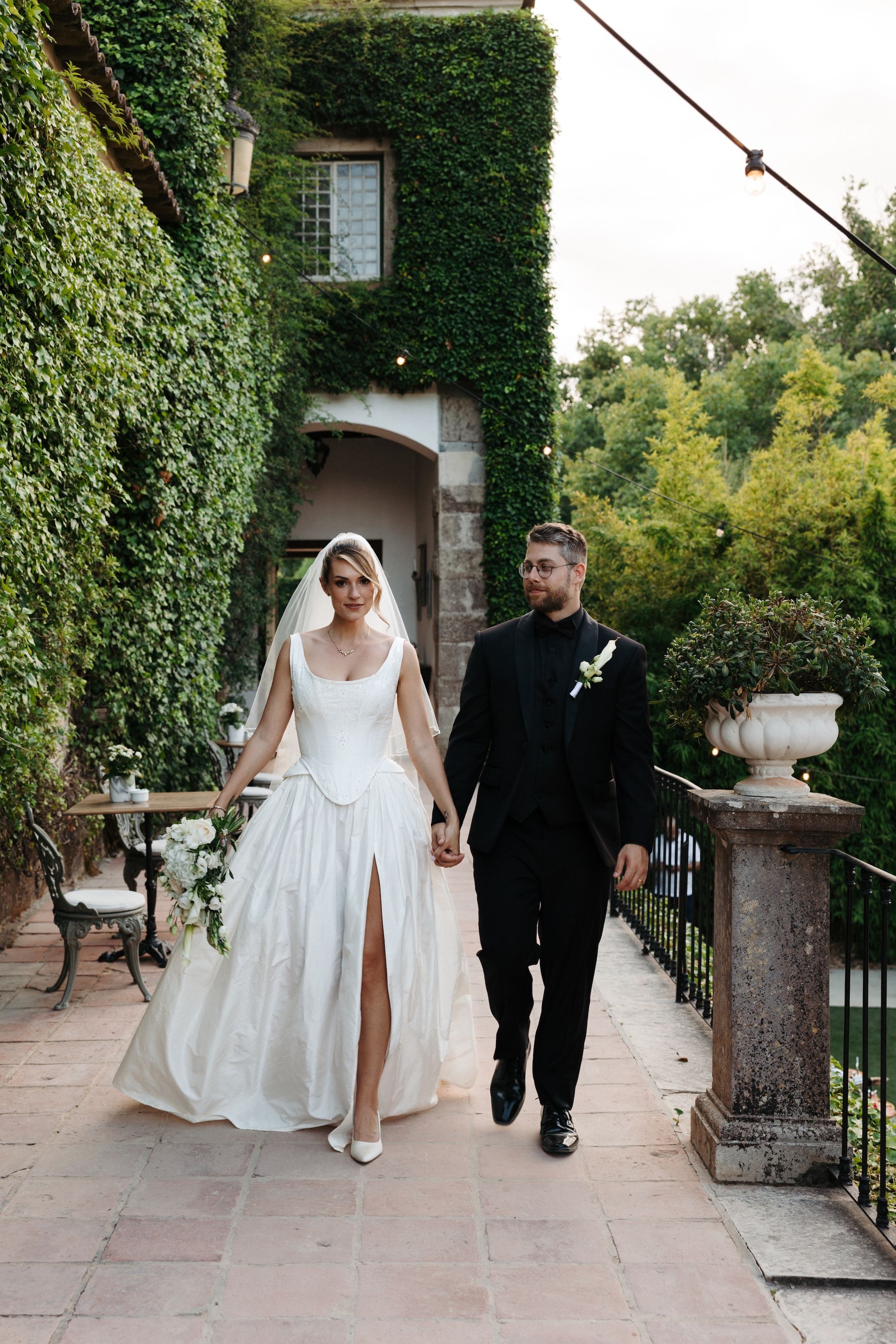 Newlyweds hold hands and walk on the palace's terrace during their small wedding in Portugal