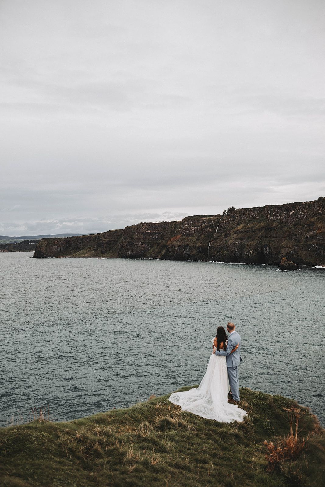 Newlyweds atop the cliffs during their autumn destination wedding in Northern Ireland, with Atlantic Ocean as the backdrop