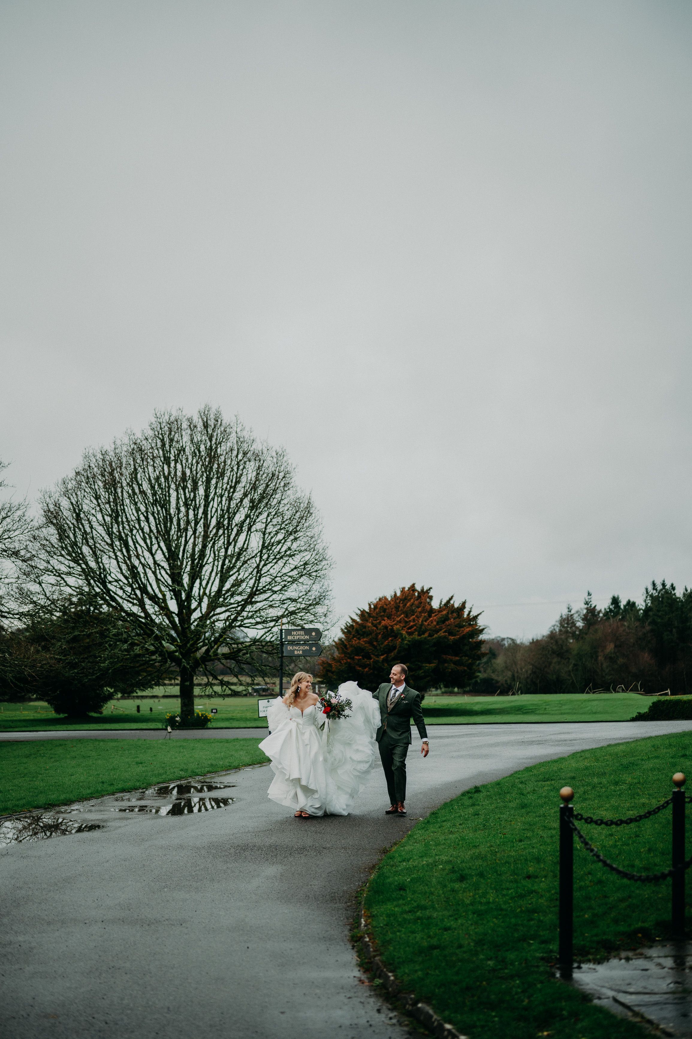 Bride and groom walking along the castle driveway during an intimate wedding in Ireland