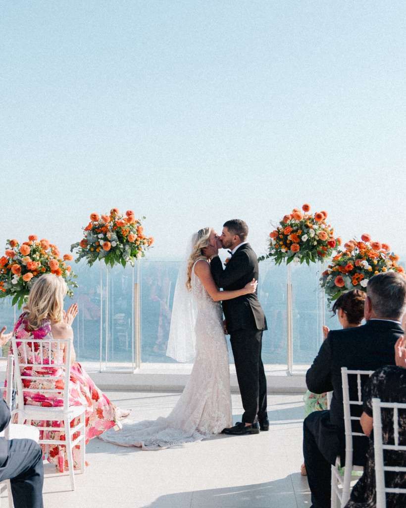 Bride and groom kiss during the ceremony of their intimate wedding in Italy with the Mediterranean Sea in the background