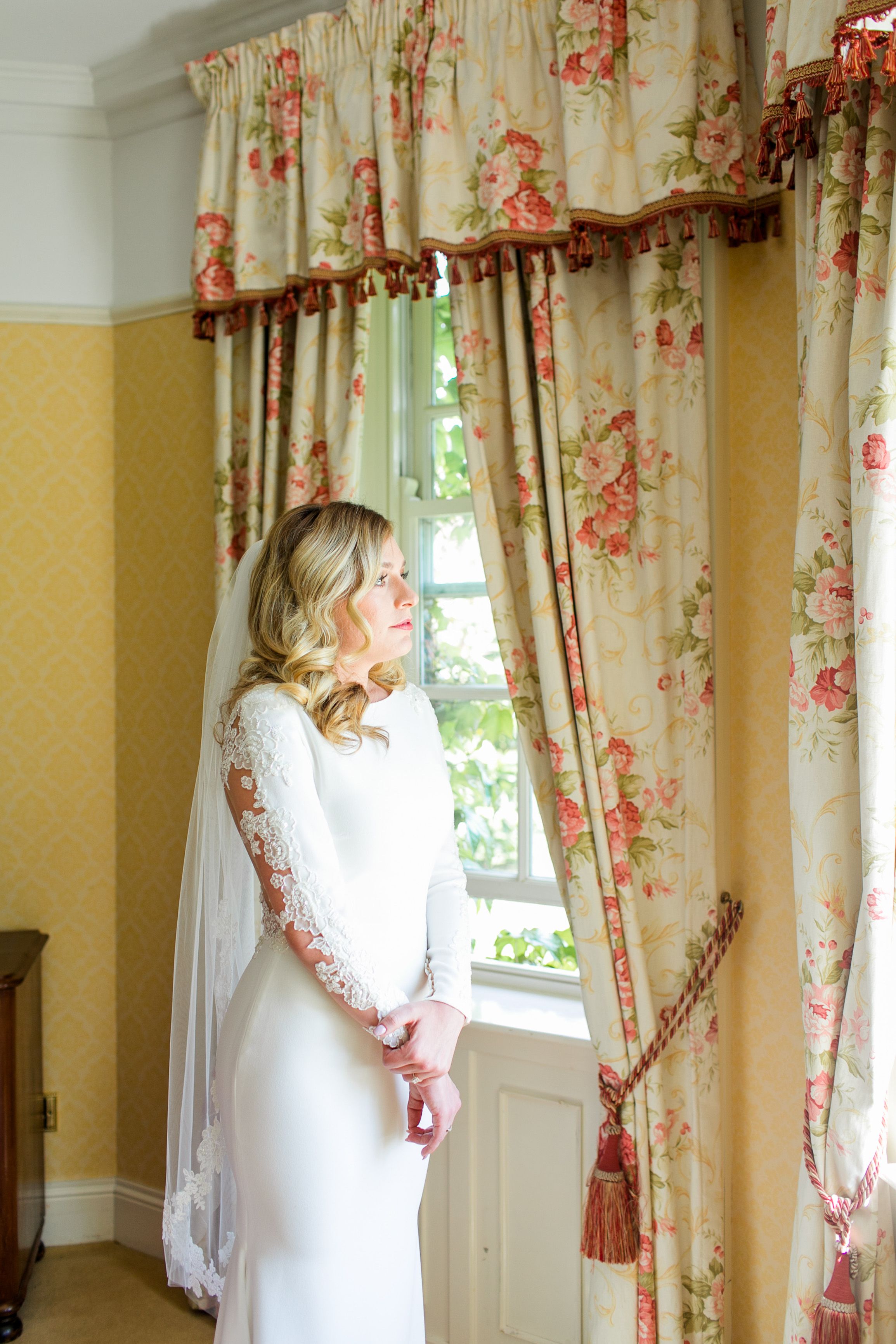 Bride looking out a window in a floral suite while getting ready for an intimate wedding in Europe