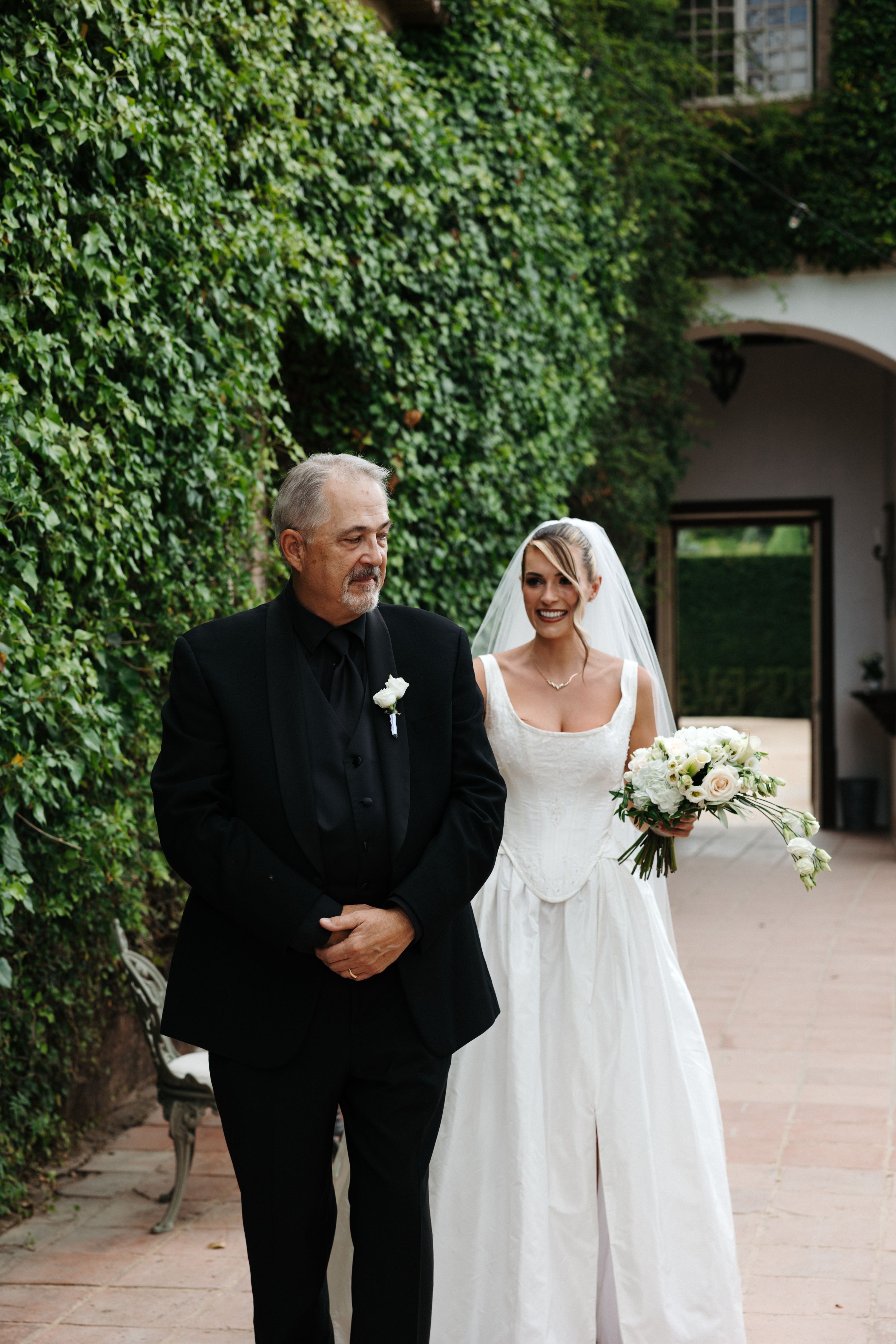 The bride standing behind her father just before he turns around to see her in her wedding dress