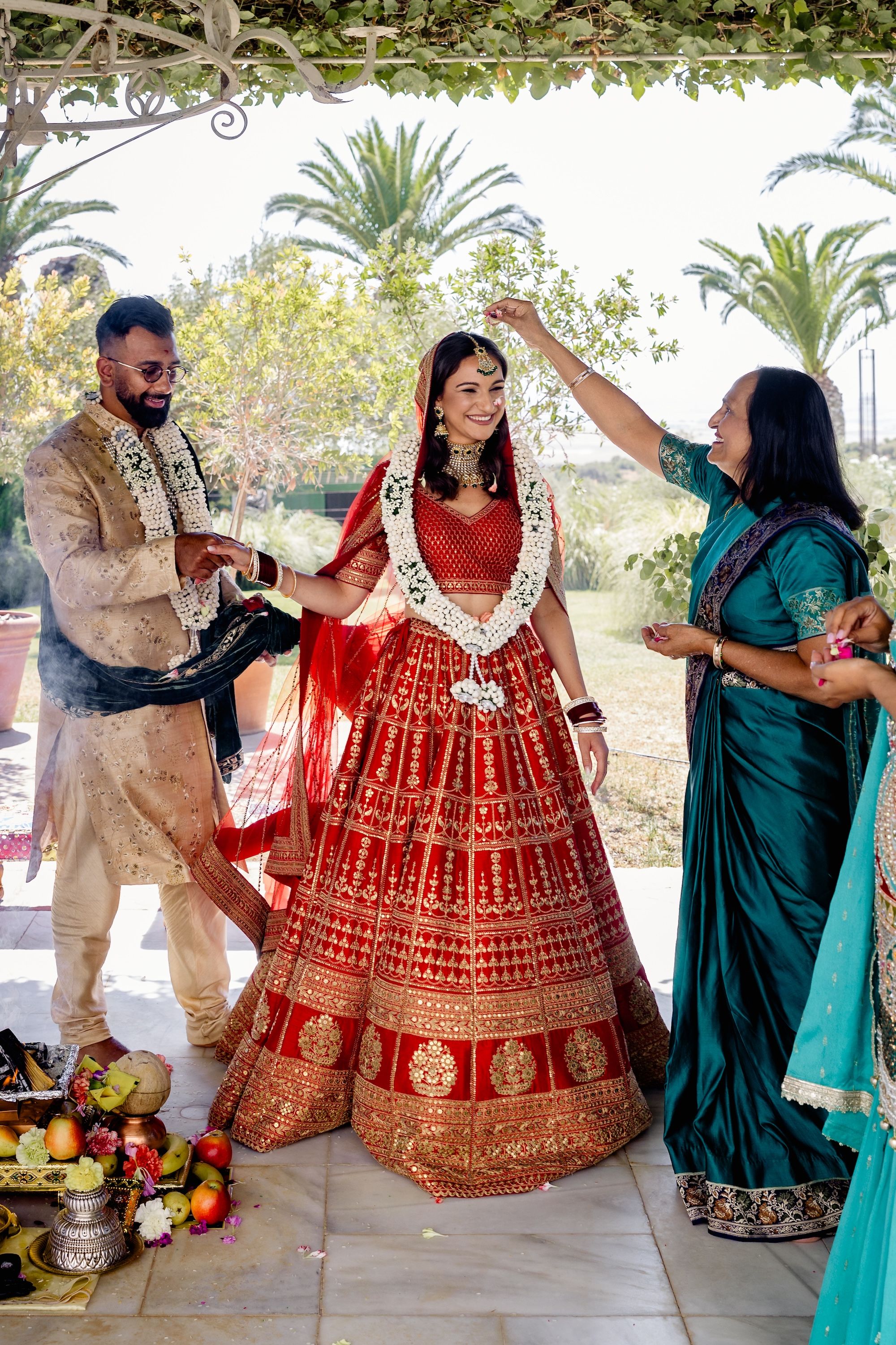 Bride and groom during a Hindu wedding ceremony with an elderly performing a ritual