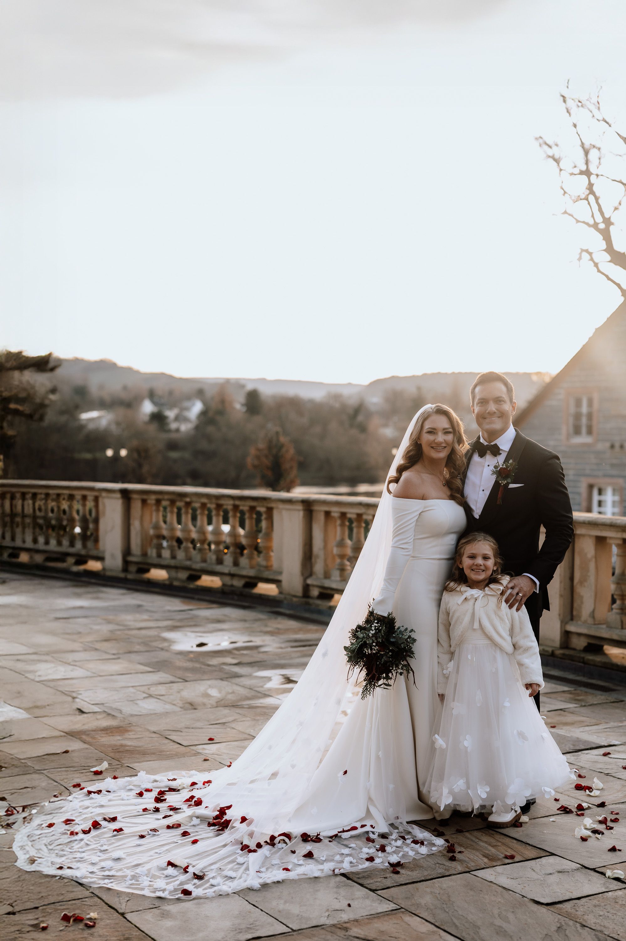 A bride and groom posing with their daughter after their small wedding in Germany
