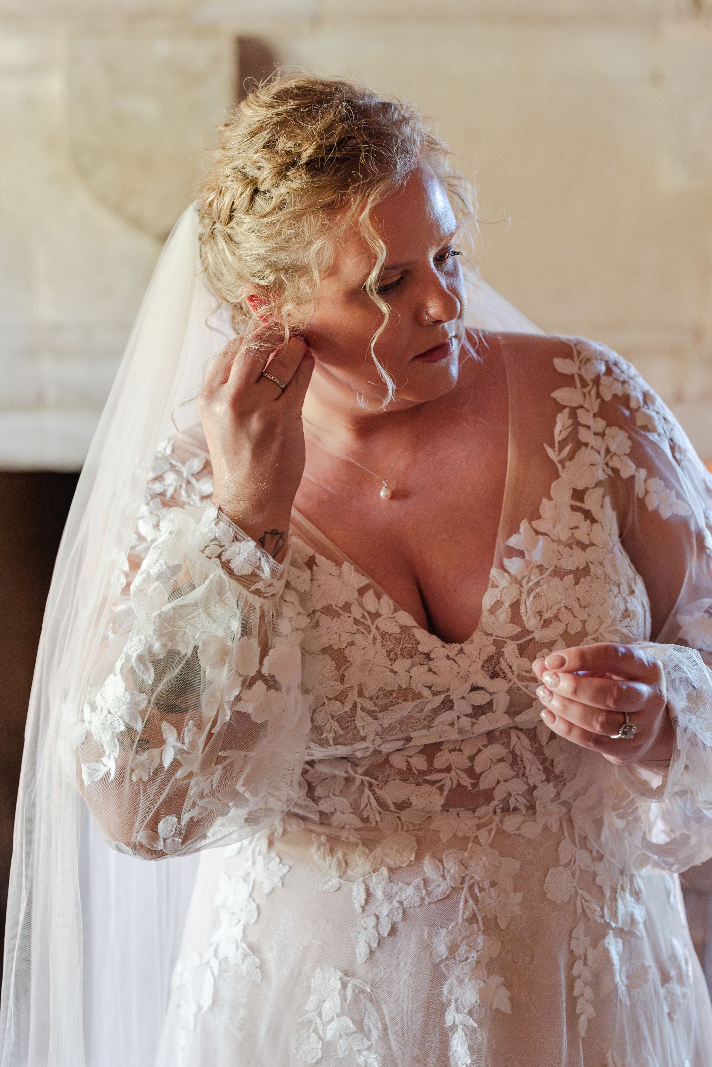 Bride adjusting her earring while getting ready for a small wedding in France
