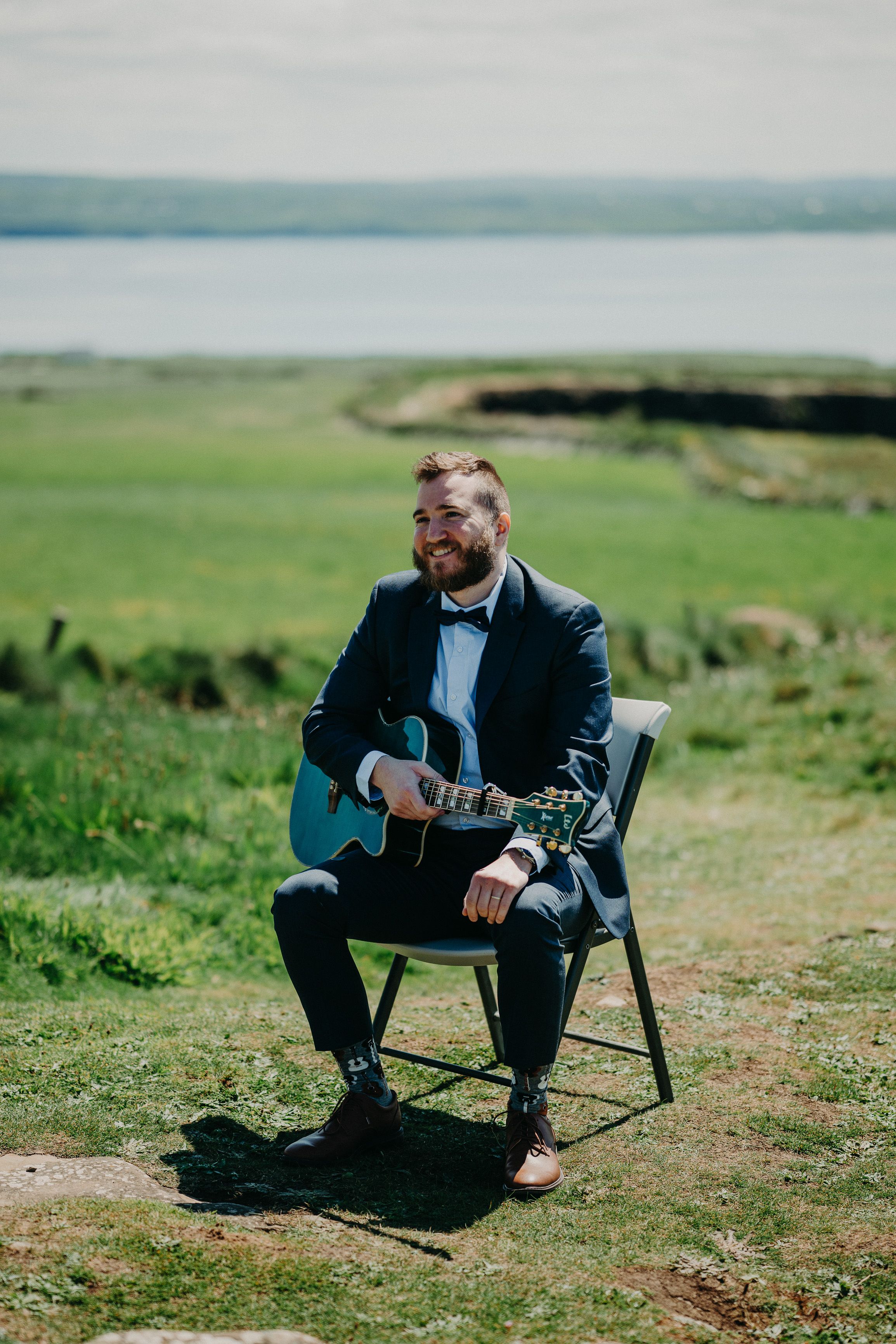 A guitarist providing quality music for a ceremony set on a cliff during a small wedding in Ireland