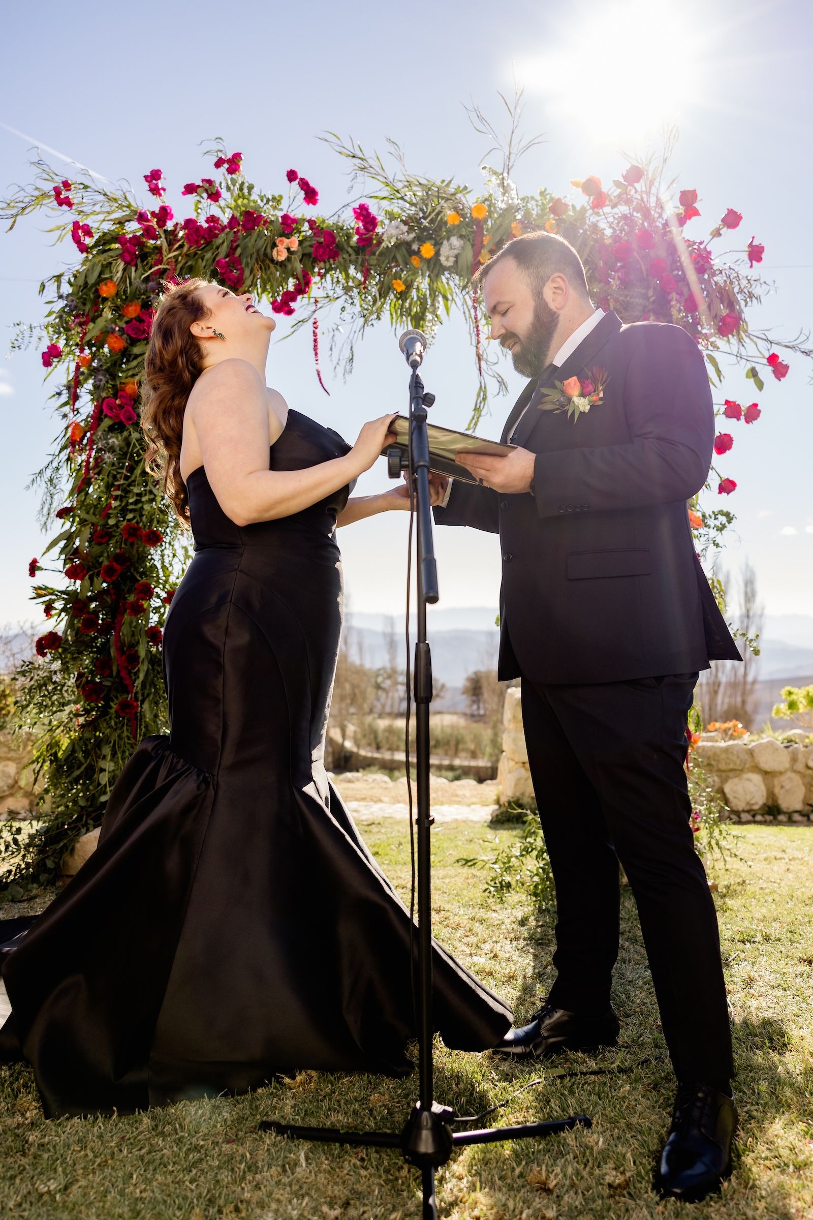 Bride laughs as the groom recites his vows in a sunny outdoor ceremony in Alenquer during a destination wedding in Spain