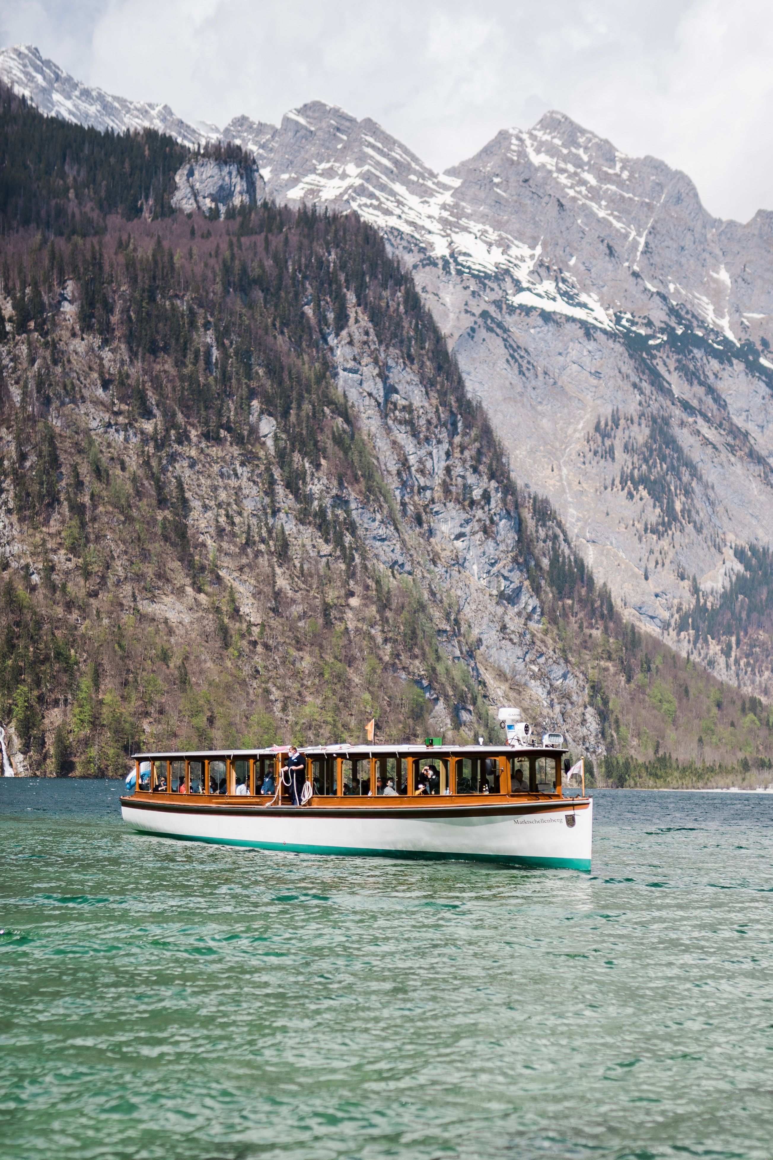 Classic passenger boat crossing an Alpine lake beneath steep cliffs