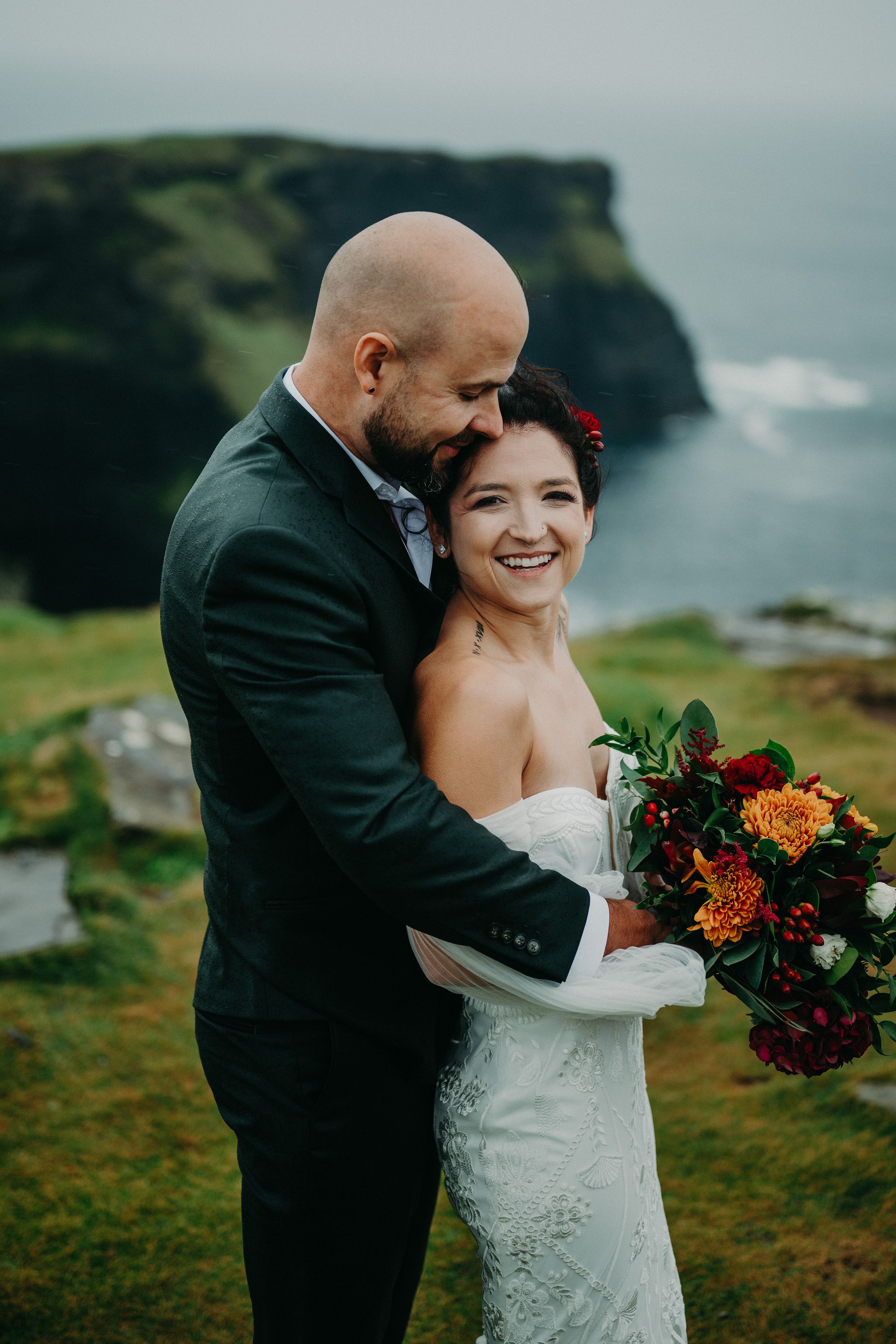 Bride and groom embracing with rugged coastal scenery after an intimate wedding in Europe