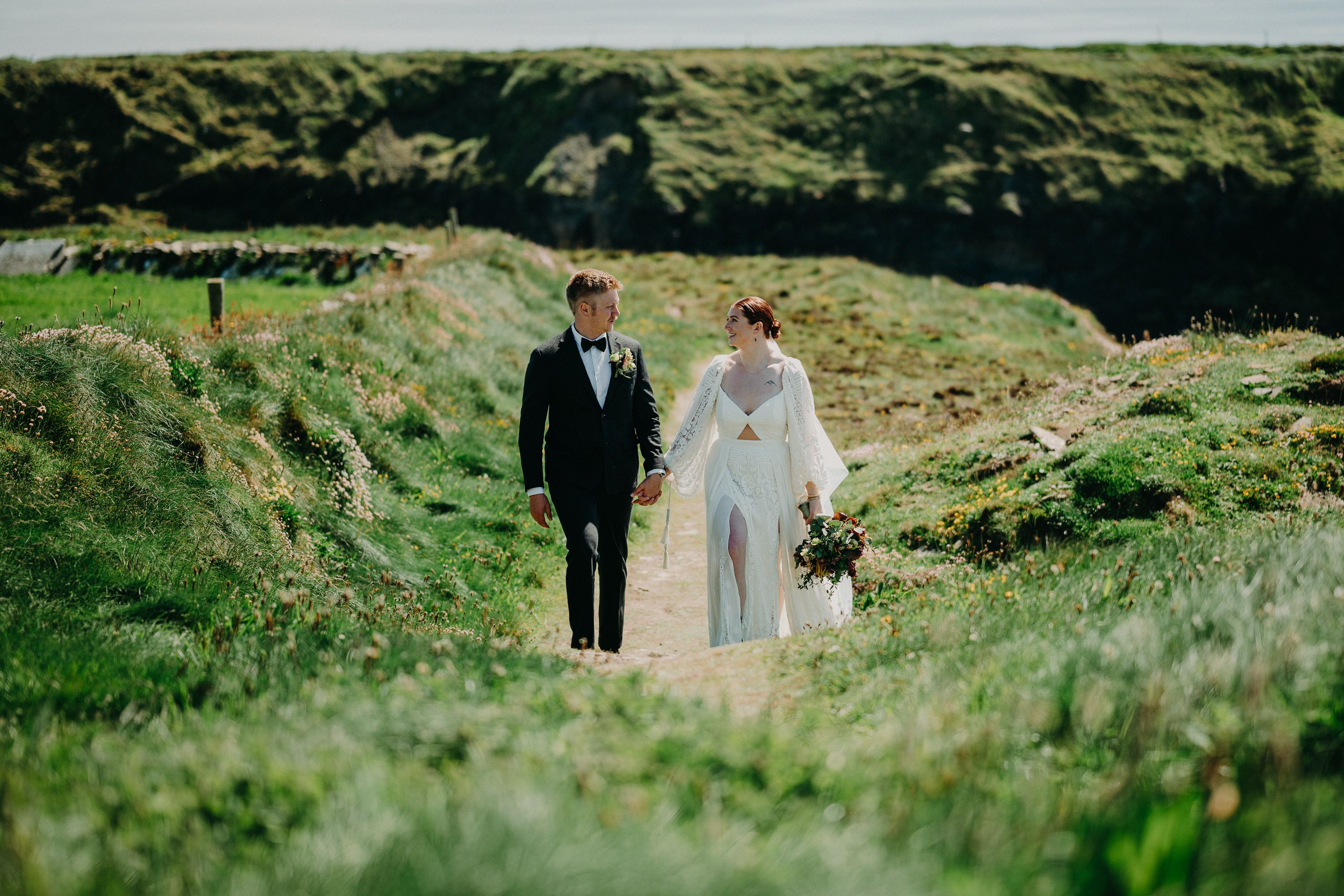 A bride and groom looking at each other while standing on a beautiful grassy path during their small wedding in Ireland