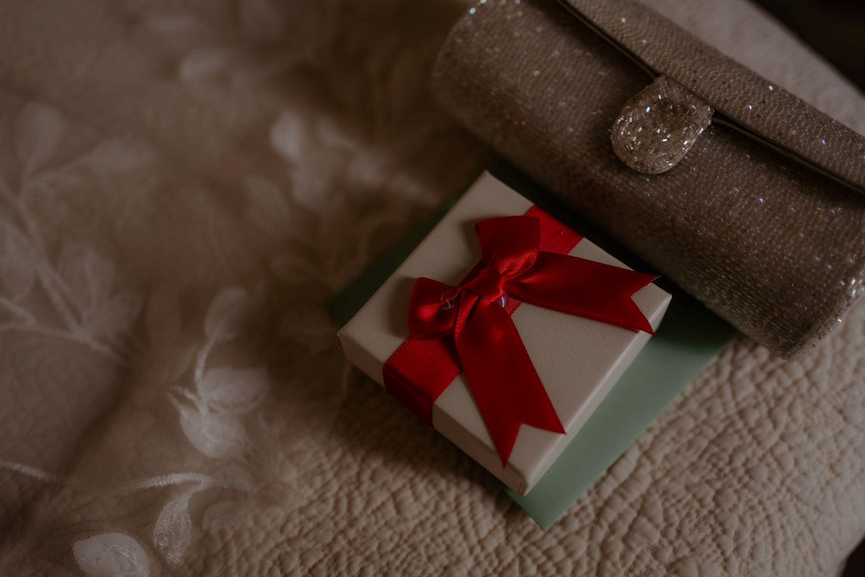 Elegant wedding gift box with red ribbon beside bridal accessories at a small wedding in Italy