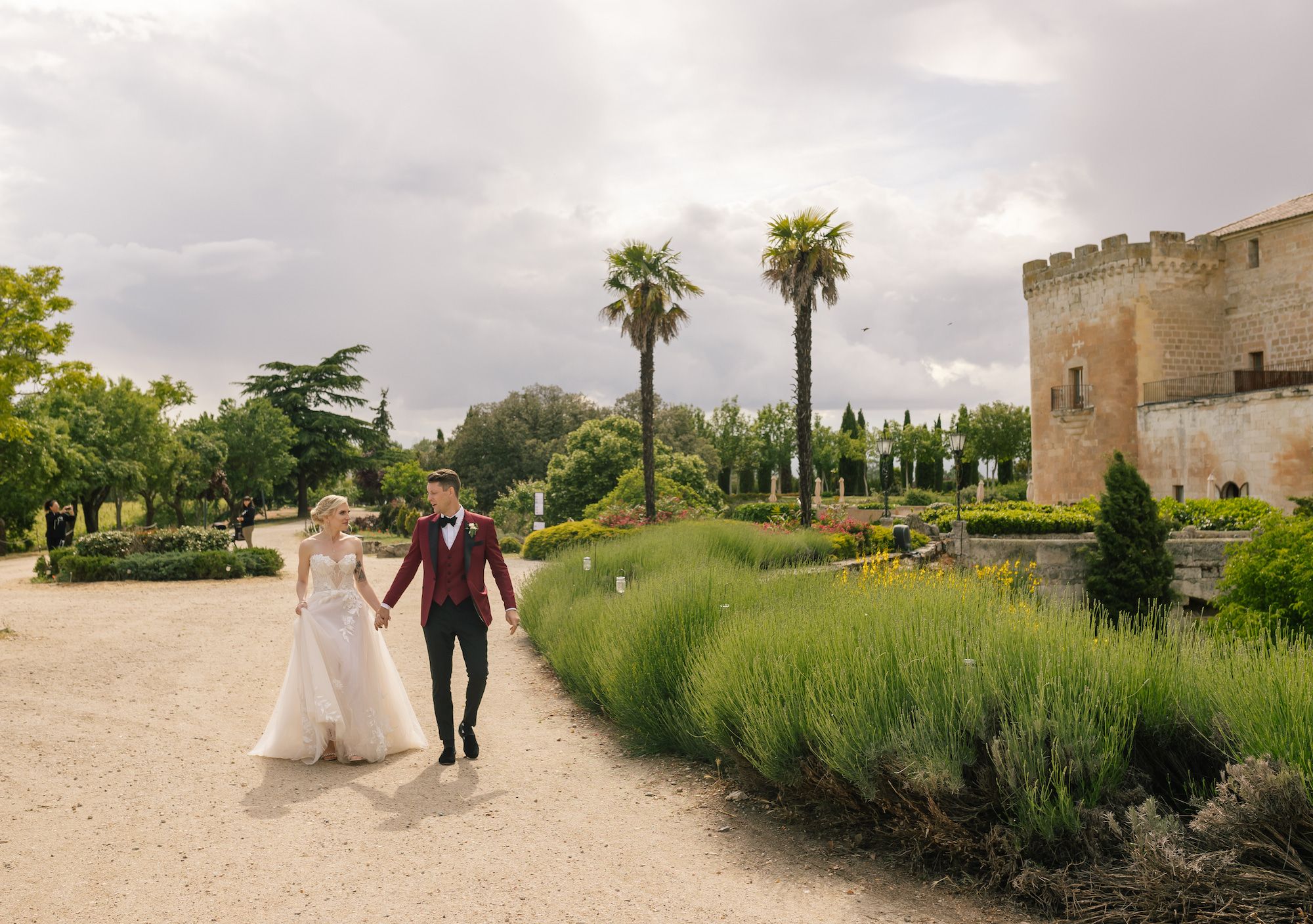 Newlyweds walk along the wide estate of the 15th-century castle that served as the venue for their destination wedding in Spain
