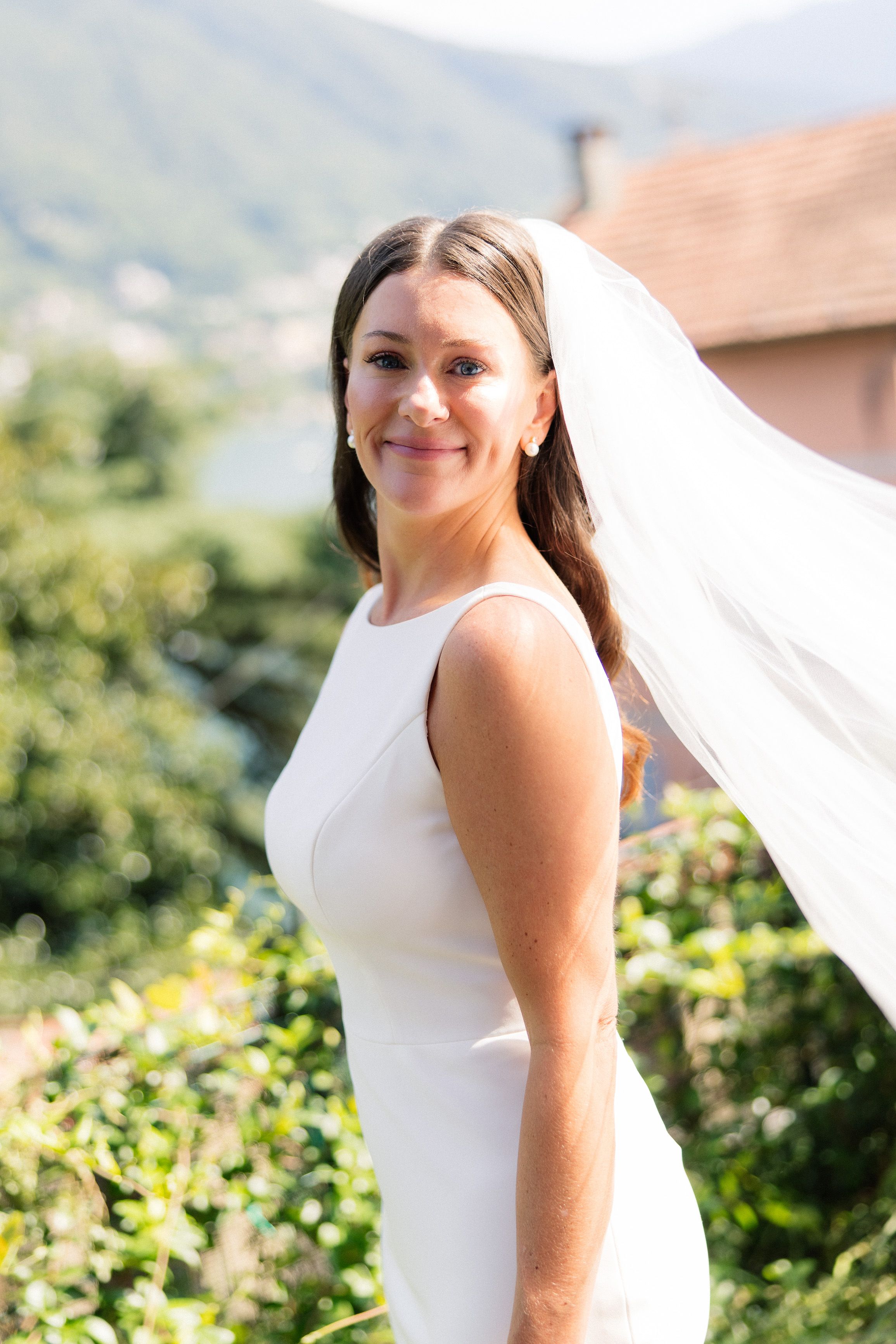 Bride in a sleek white gown with flowing veil overlooking Lake Como during a small wedding in Italy