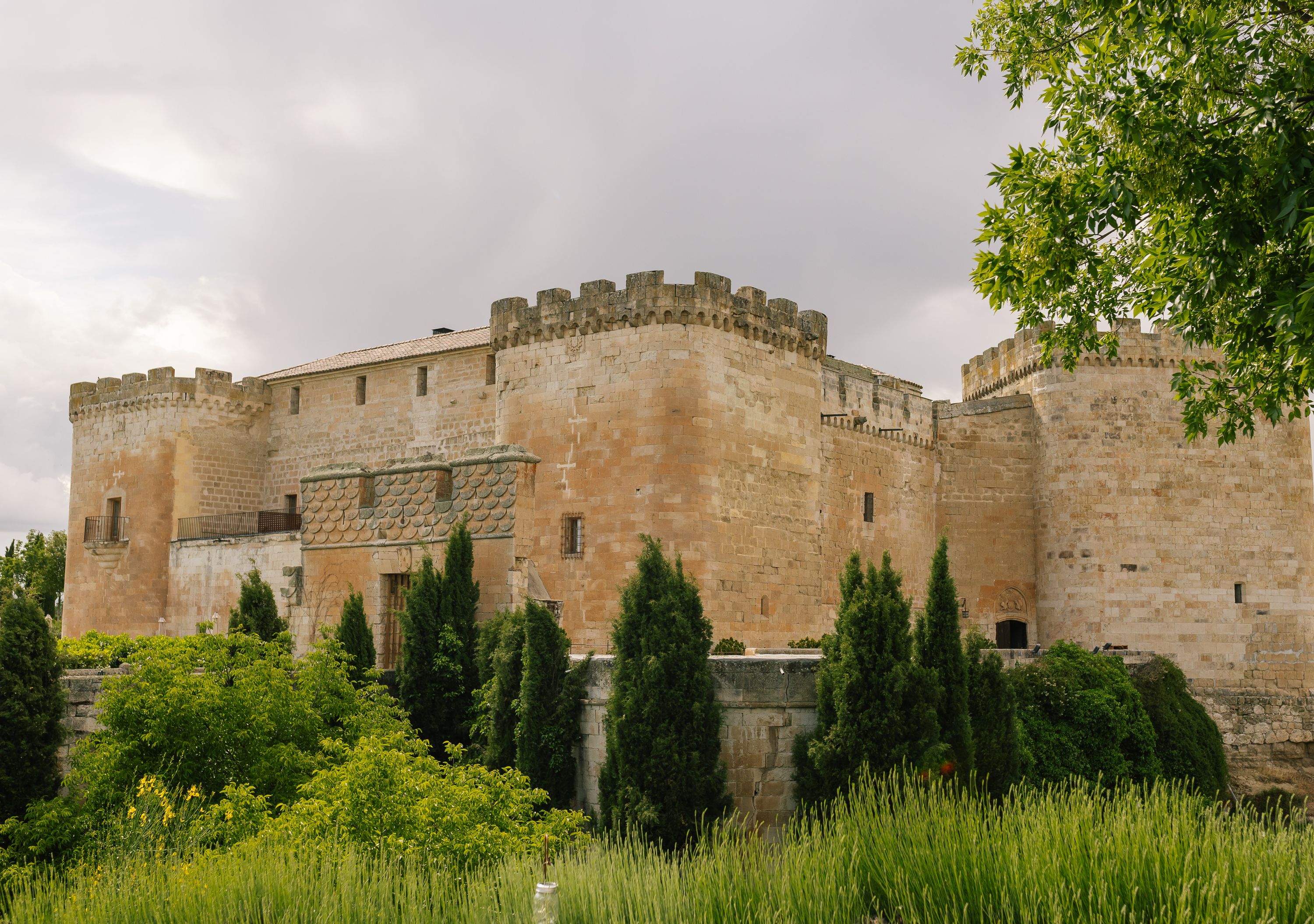 A historic castle with medieval brick facade set against the lush greenery of Salamanca in Spain