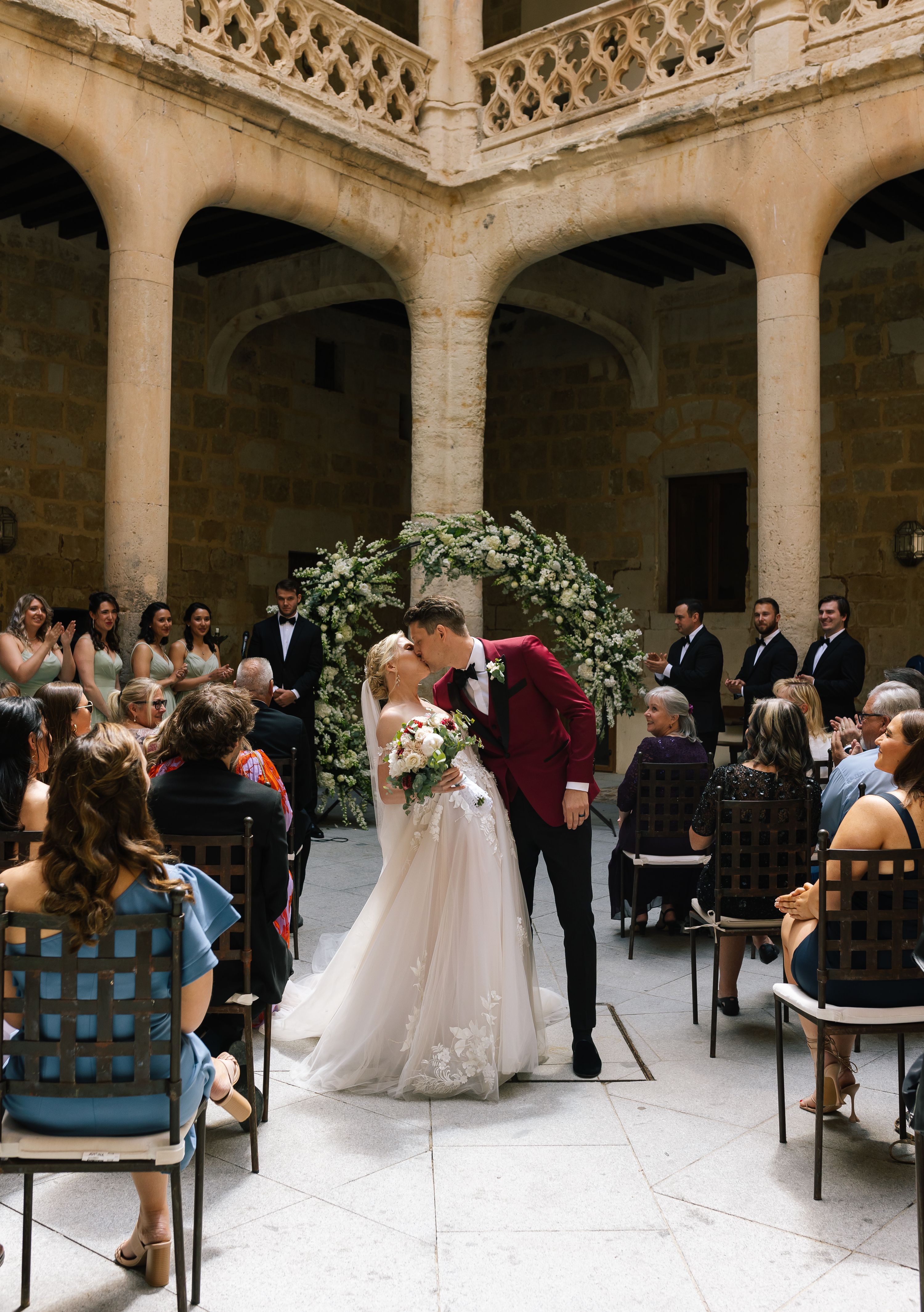 Bride and groom kissing in the middle of the aisle in the castle’s courtyard during their destination wedding in Spain