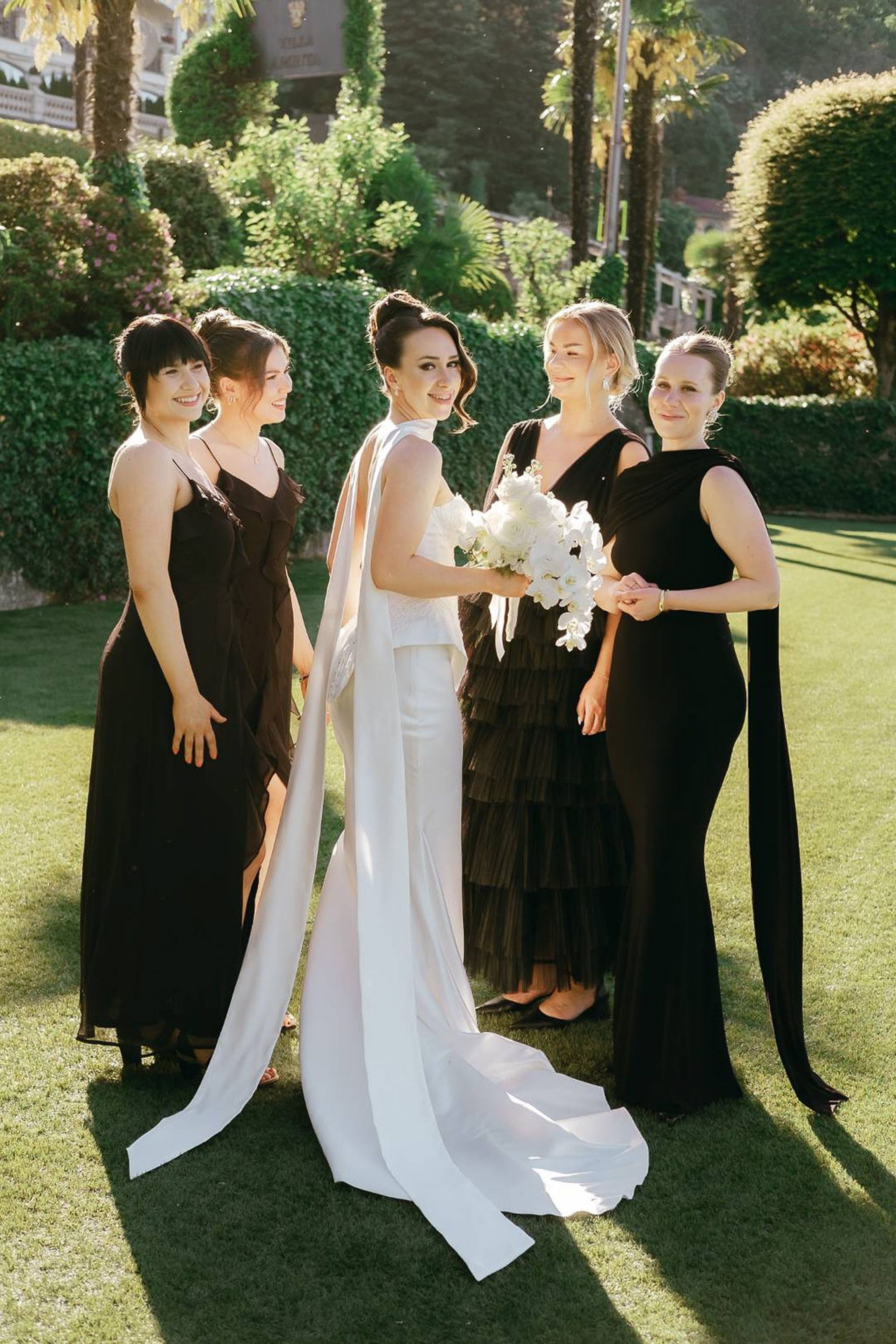 Bride posing with bridesmaids in elegant black dresses during an intimate wedding in Italy