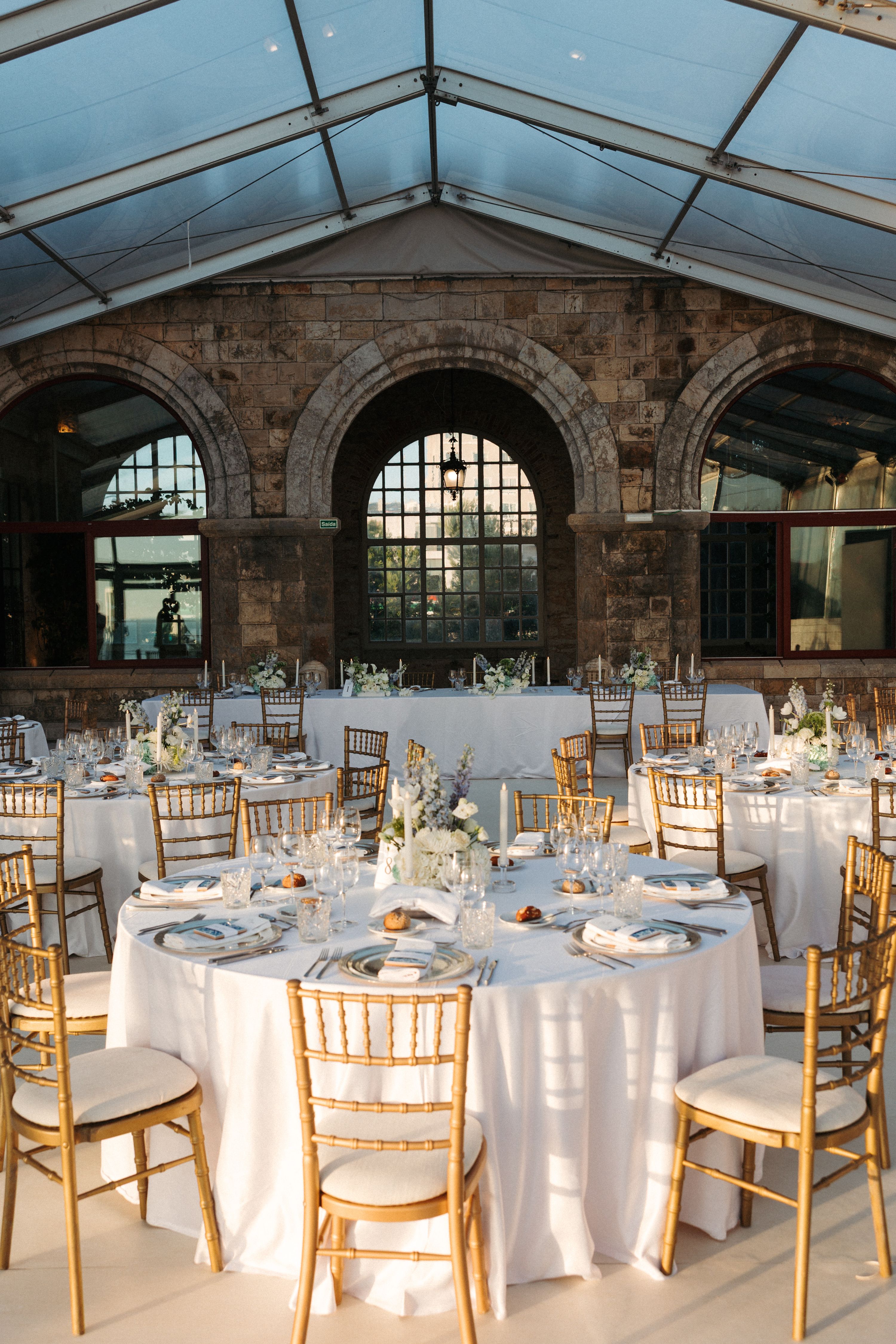 Castle walls and a white marquee with golden chairs and white tables arranged for a wedding reception in Portugal