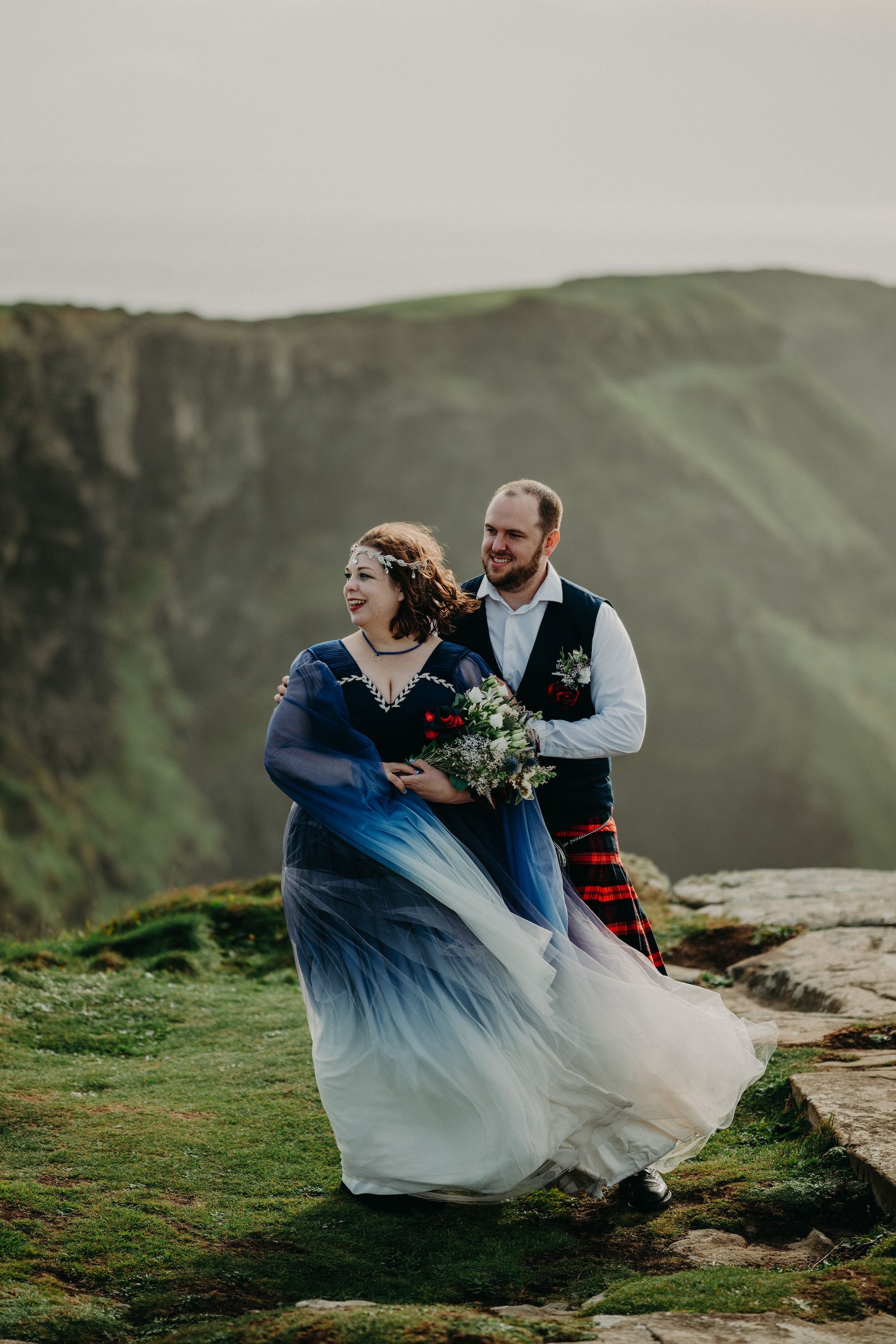 Bride and groom on top of Hag’s Head cliffs hugging on a windy day when they got married in Ireland
