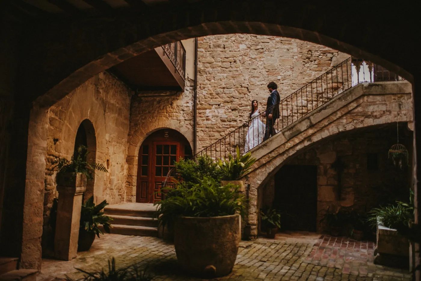 Bride and groom descending from the staircase of a medieval castle in Spain