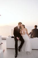 Newlyweds kissing while holding glasses of champagne during the reception of their destination wedding in Italy