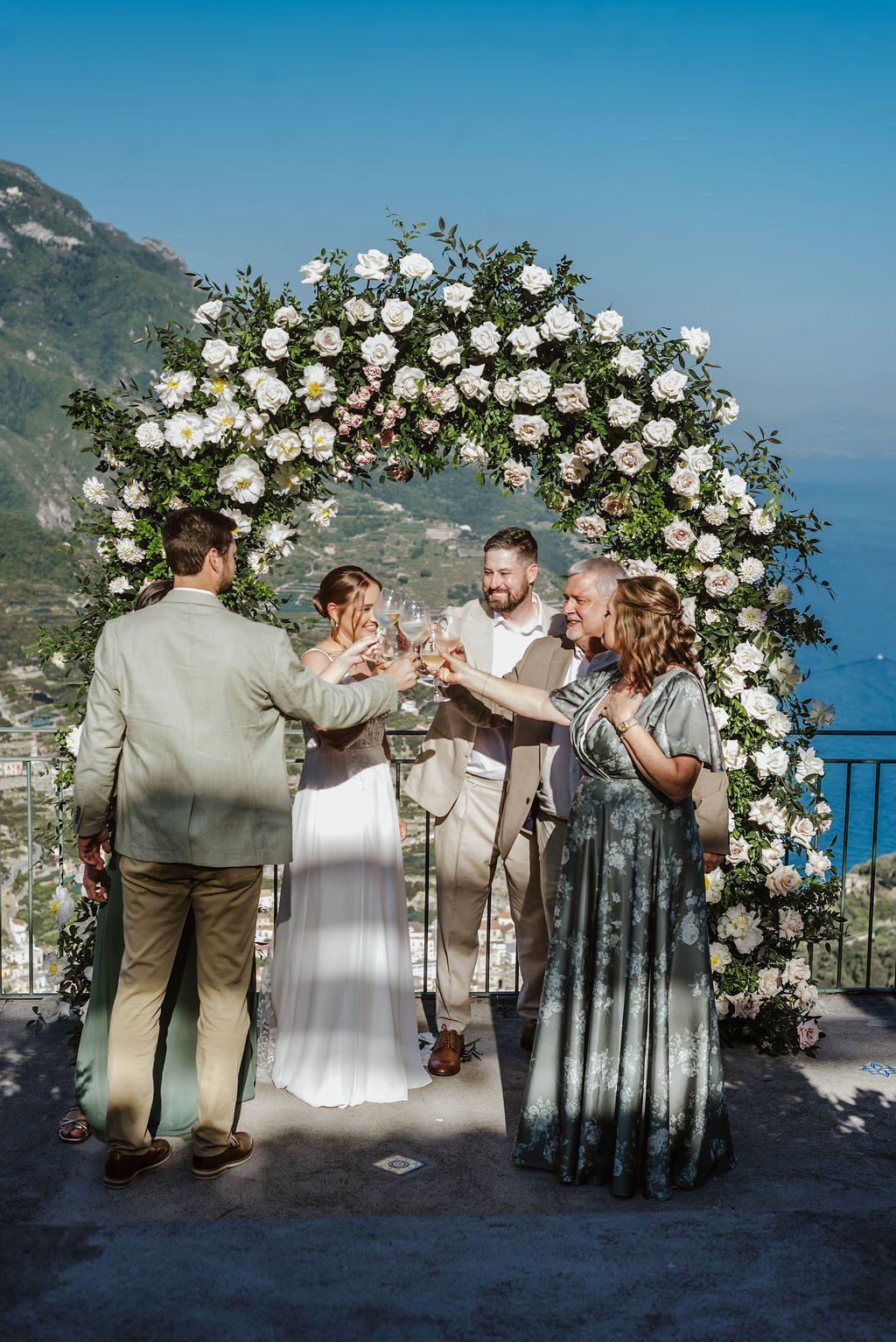 Bride and groom toast champagne glasses with their family members when they eloped in Italy