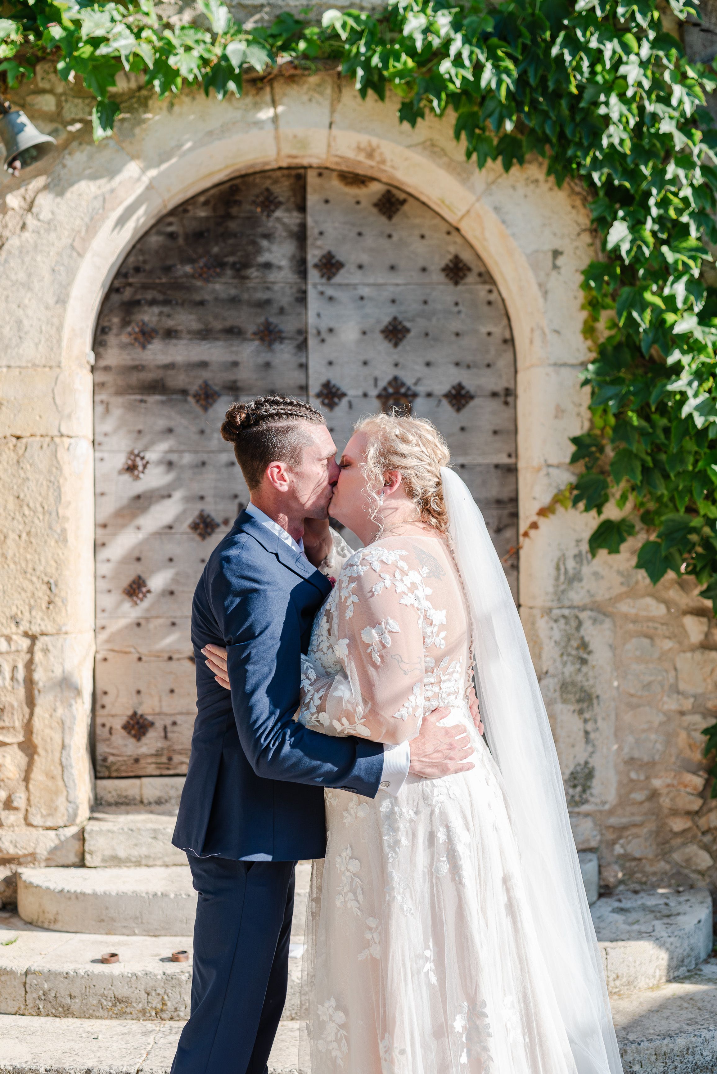 Newlyweds sharing their first kiss outside a rustic venue at an intimate wedding in France
