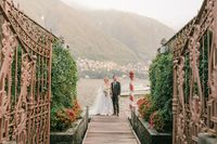 Bride and groom posing in front of ornate gates at their micro wedding in Italy