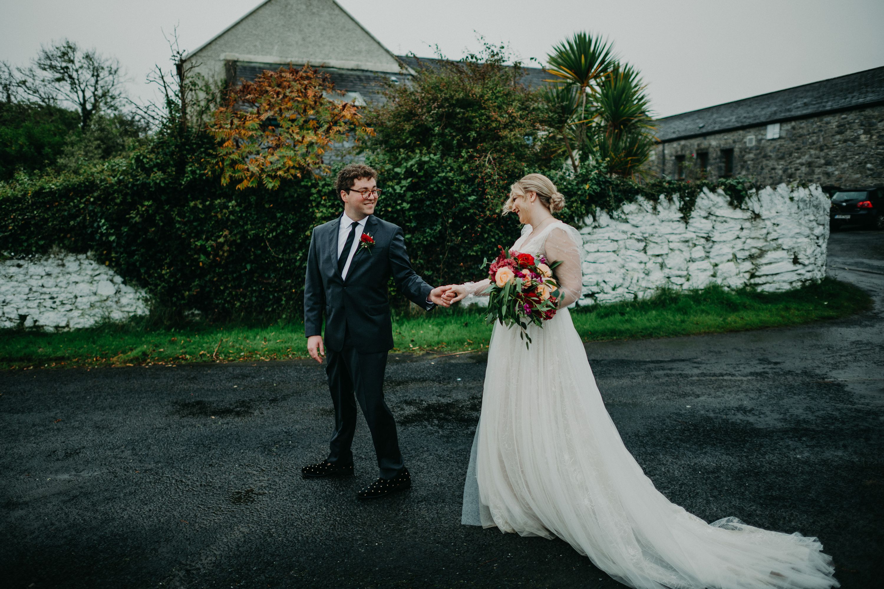 Couple walking beside a traditional stone wall following a small wedding in Ireland