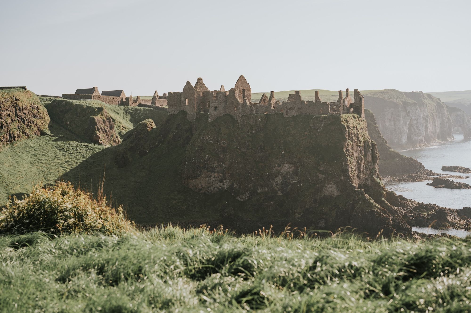 Castle ruins perched at the edge of a cliff with Atlantic Ocean underneath in Northern Ireland