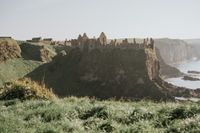 Castle ruins perched at the edge of a cliff with Atlantic Ocean underneath in Northern Ireland