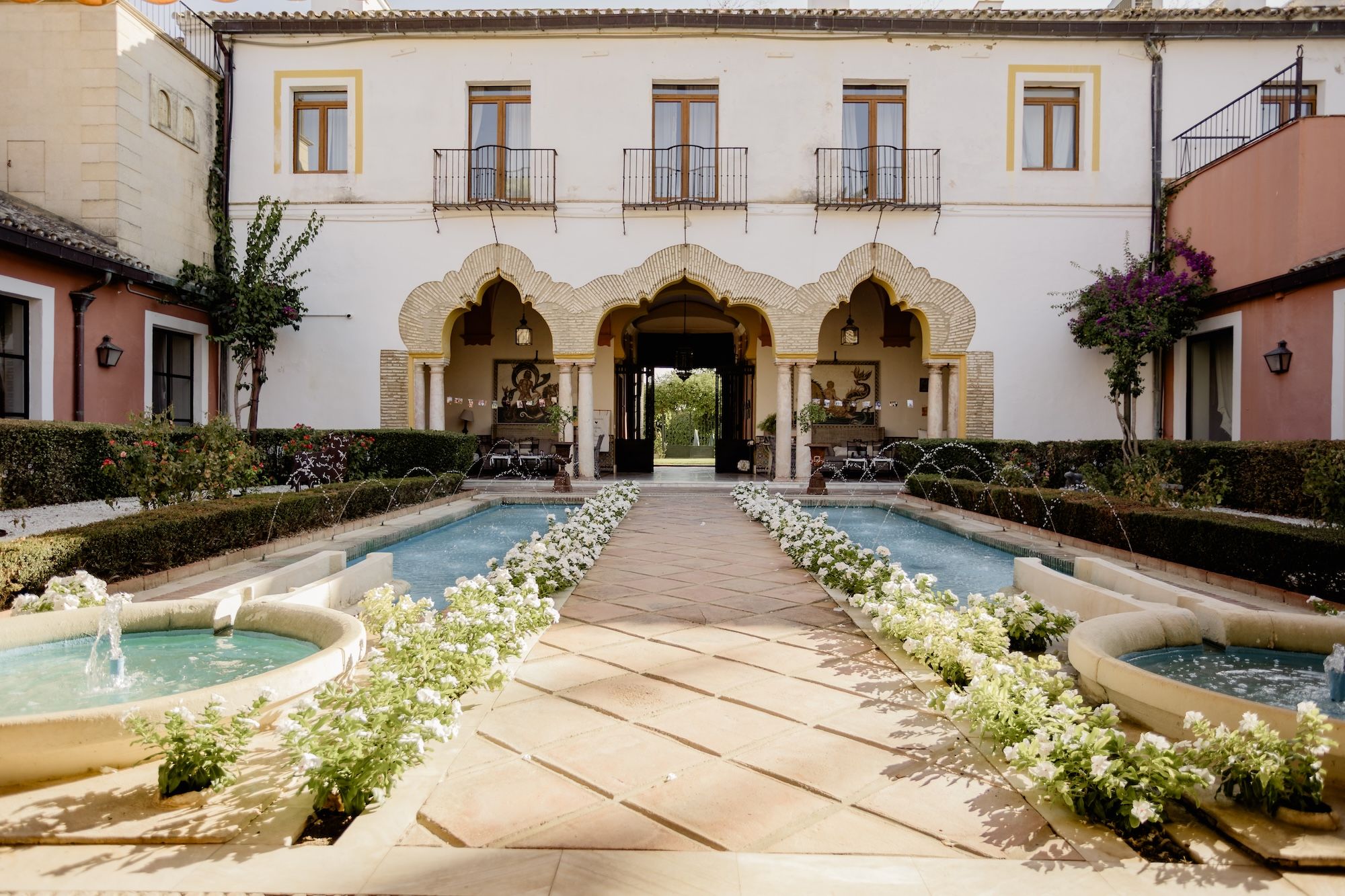 A Muslim-inspired facade of a castle with a pathway framed with greenery and small ponds on both sides