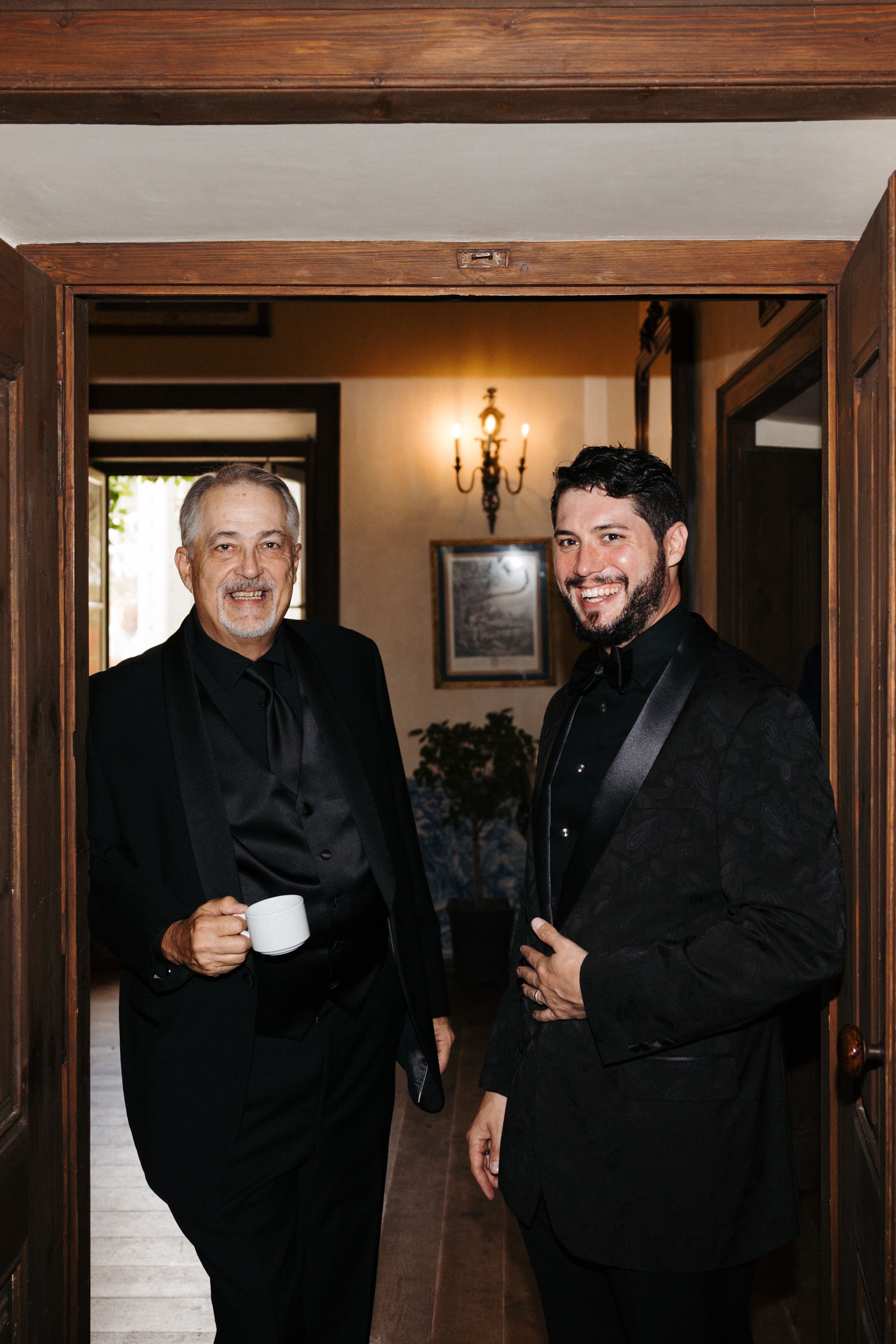 Two wedding guests standing in the doorframe and smiling