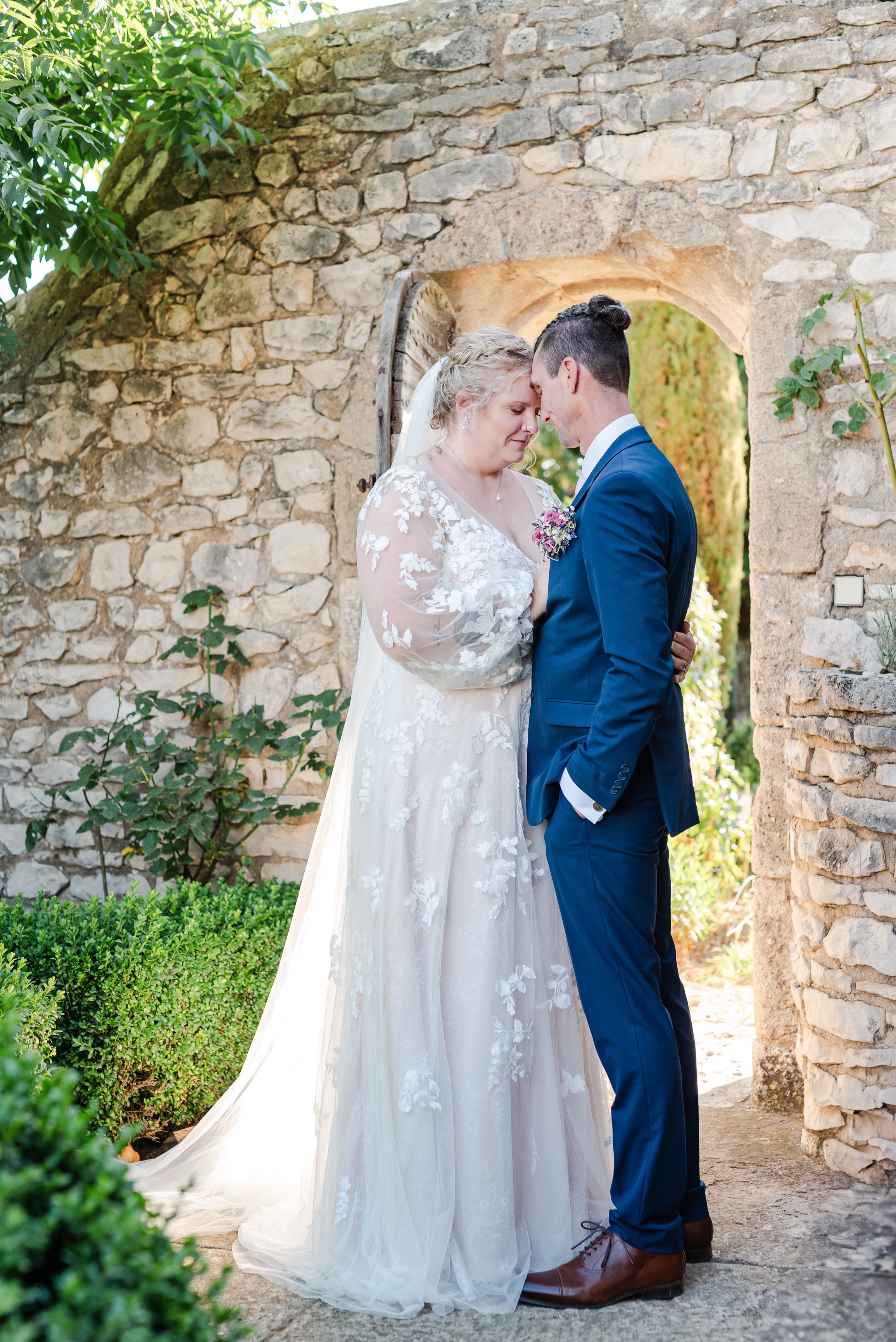 Bride and groom sharing a quiet moment beneath a stone arch during an intimate wedding in France