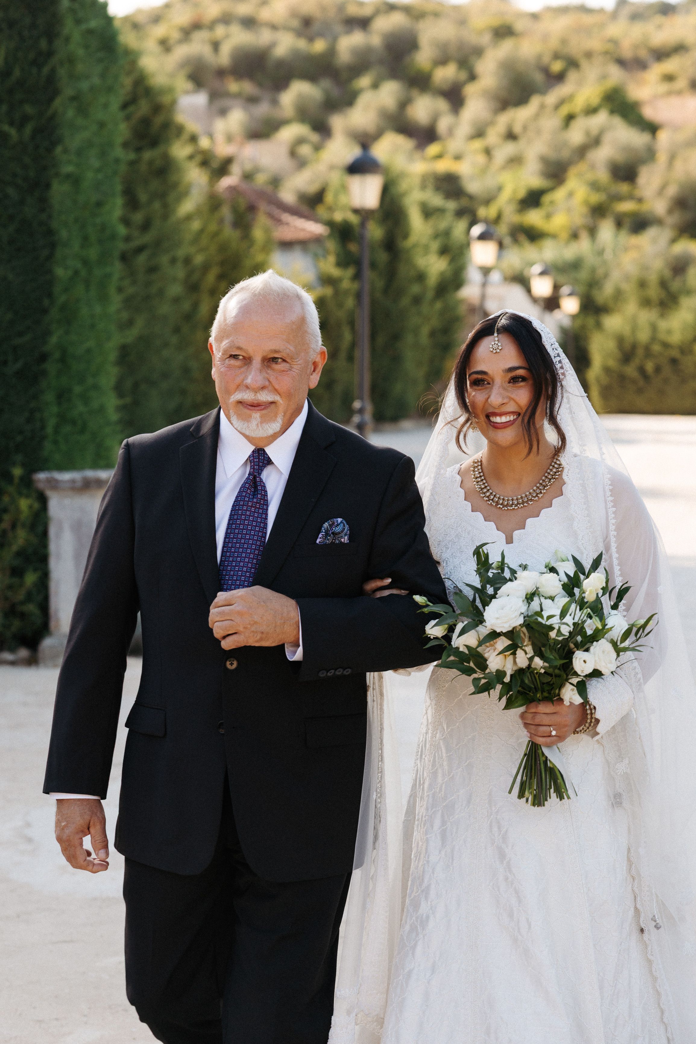 Bride walking down the aisle with her father at an intimate wedding in Portugal surrounded by greenery
