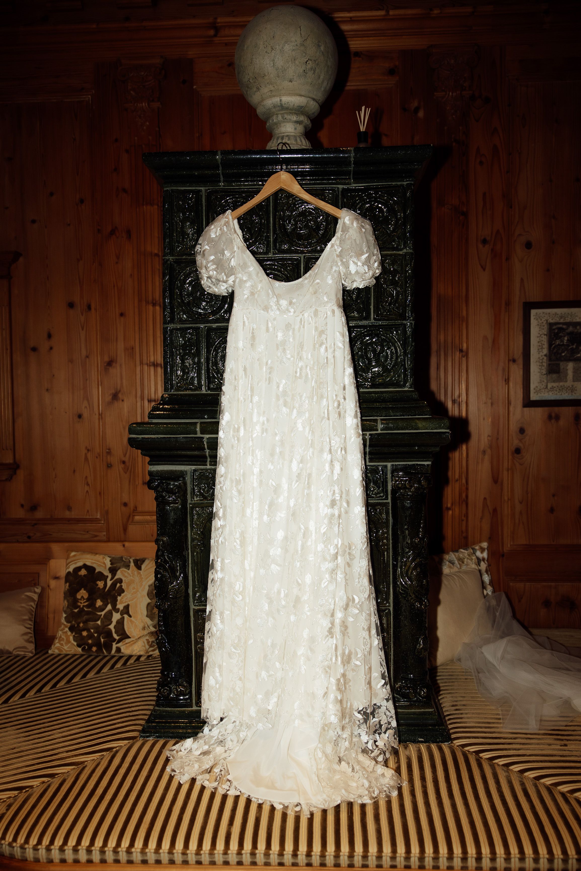 Lace wedding dress hanging in a rustic room before a small wedding in Austria
