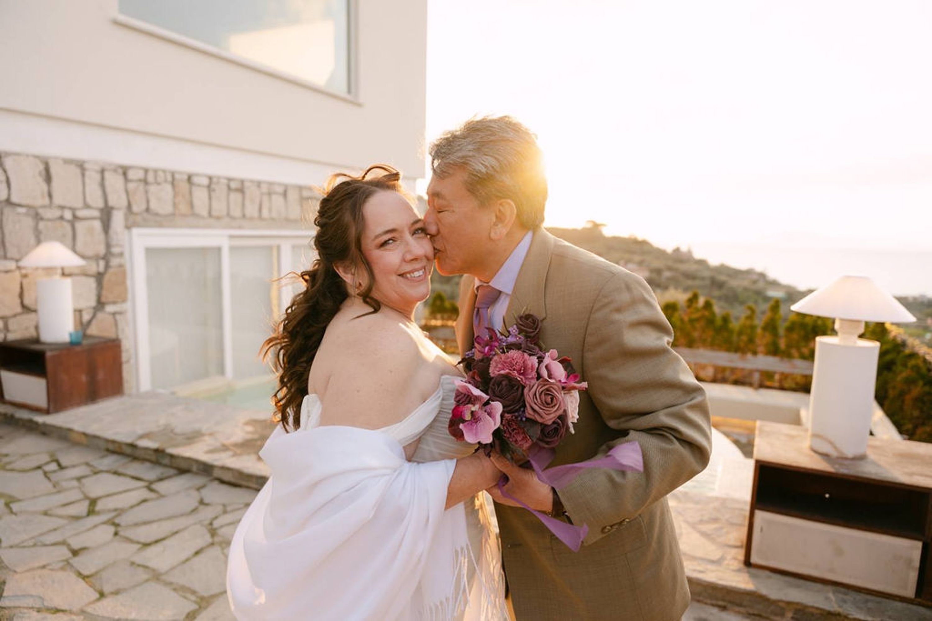 Newlyweds sharing a kiss at sunset during an intimate wedding in Italy with coastal views