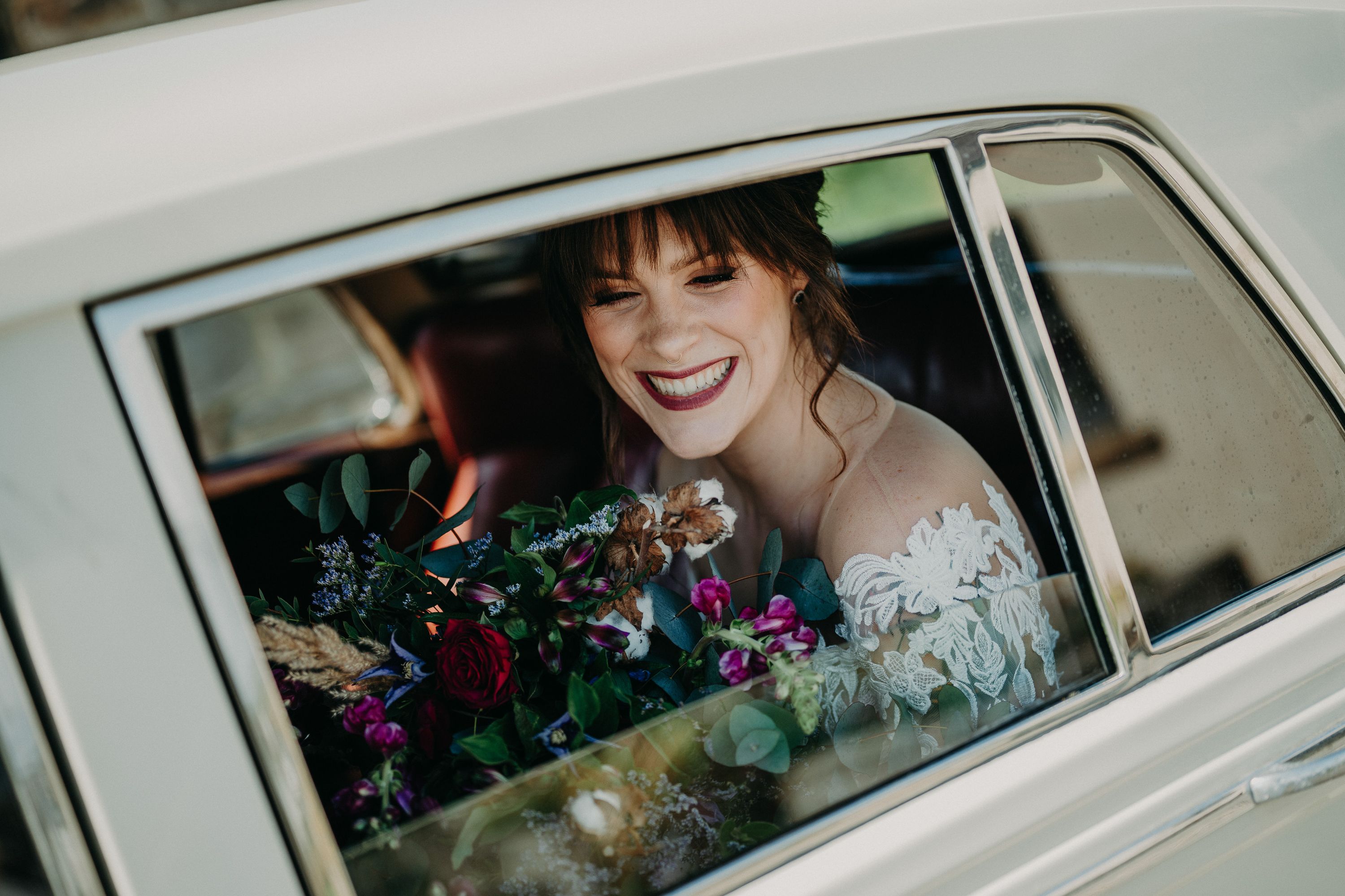 A bride smiling inside a car as she heads to her small wedding in Ireland