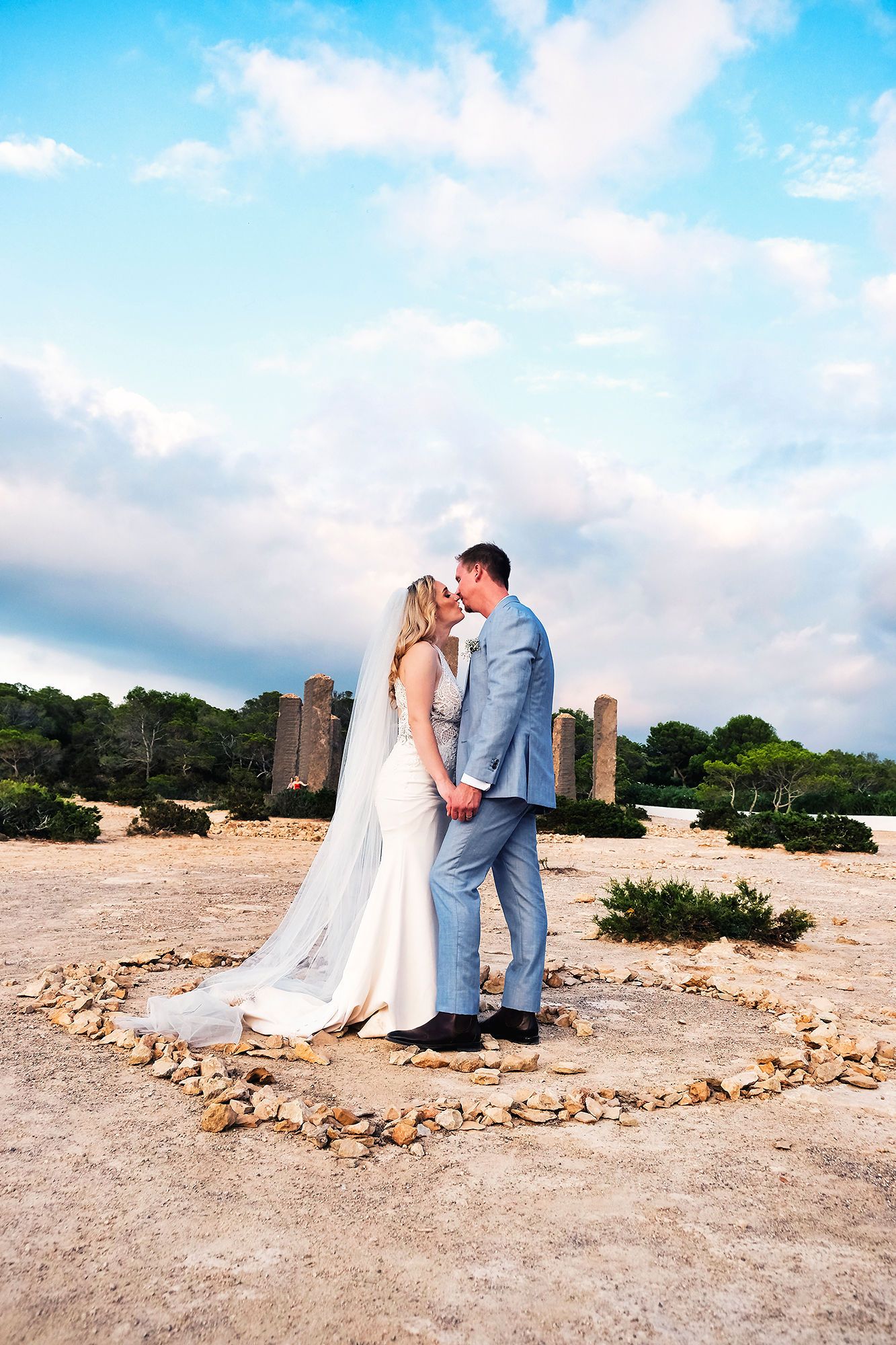 Bride and groom kissing and holding each other’s hands after the ceremony of their elopement in Spain at Cala Llentia, Ibiza