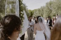 Groom looks at his bride with their guests in the background during an outdoor ceremony of an intimate wedding in Portugal