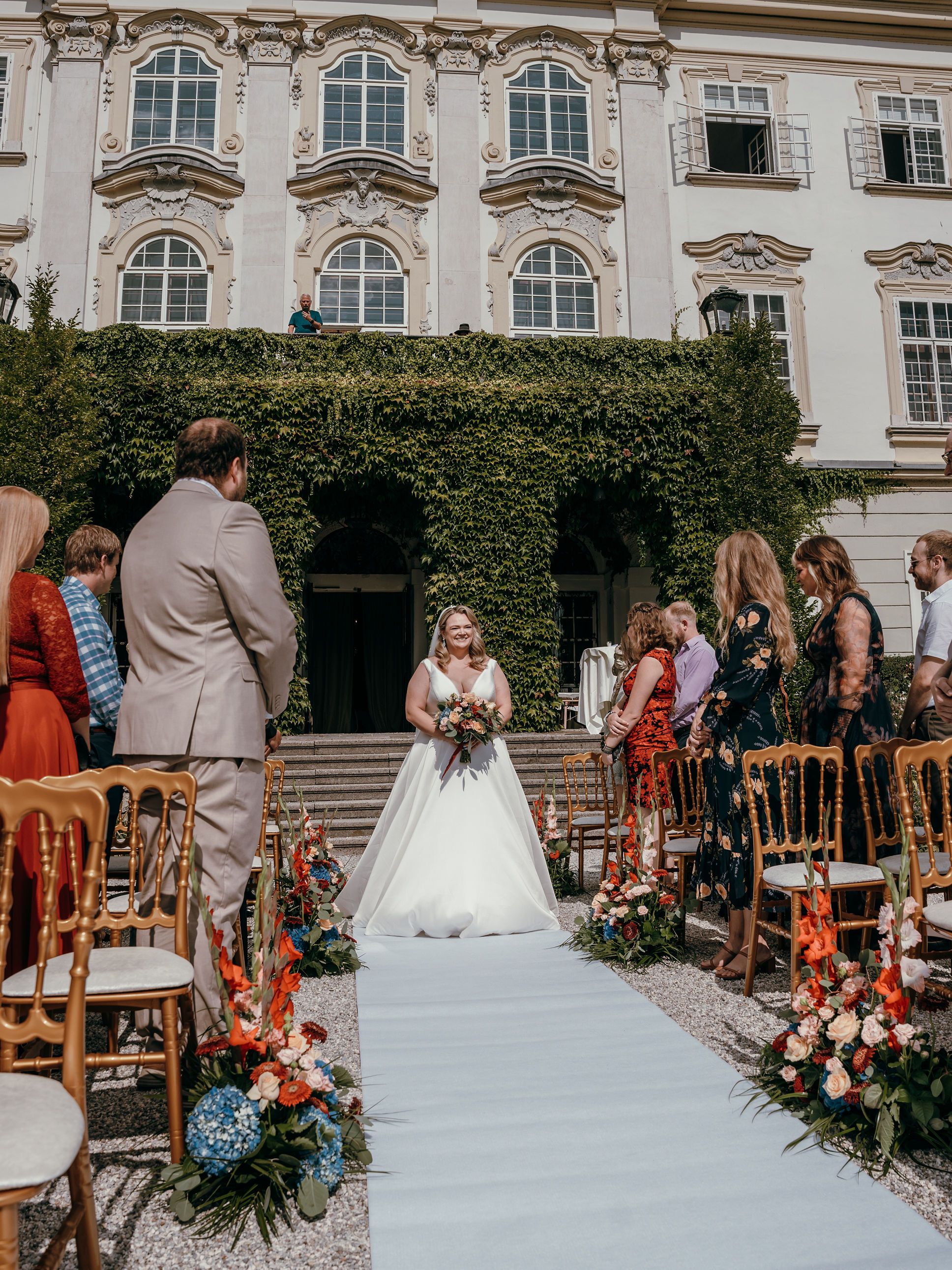 Bride walking down the aisle in front of an ivy-clad palace facade in Salzburg