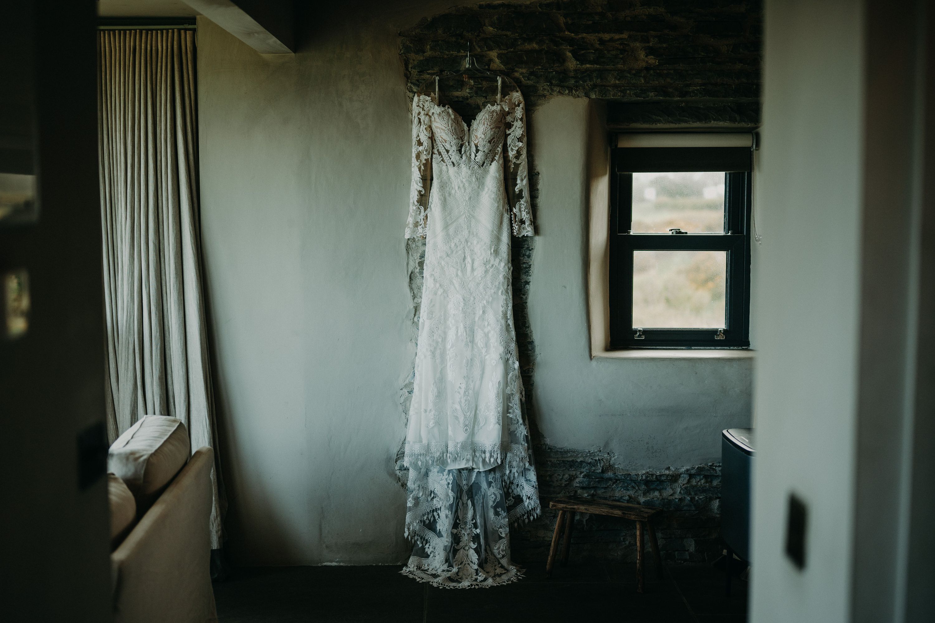 A white dress hanging on a wall inside a fairytale cottage for an elopement in Ireland