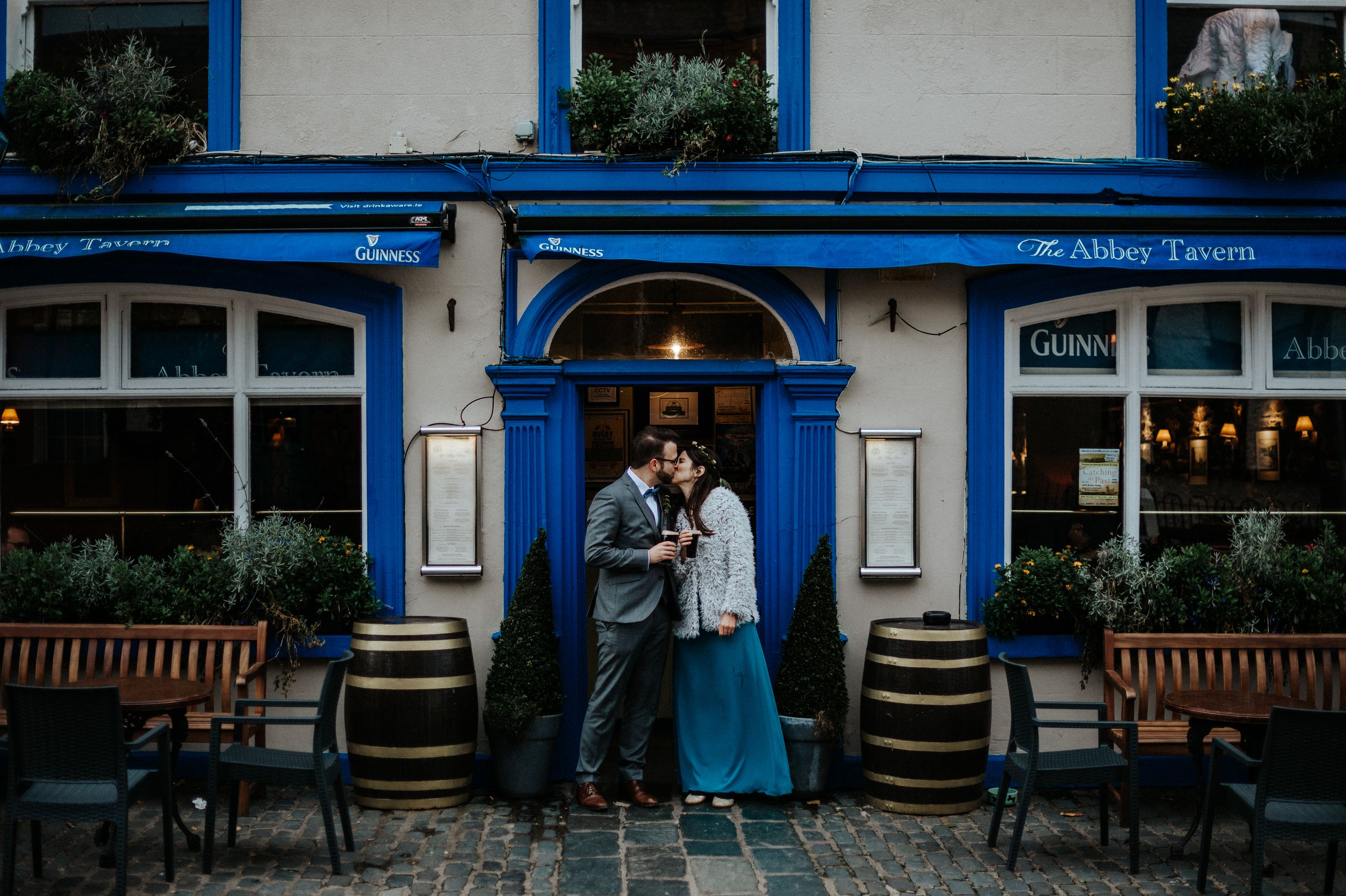 a groom and abride wearing blue in front of an Irish pub
