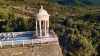 A scenic photo of the newlyweds kissing inside a marble temple in a clifftop venue in Mallorca during their small wedding in Spain